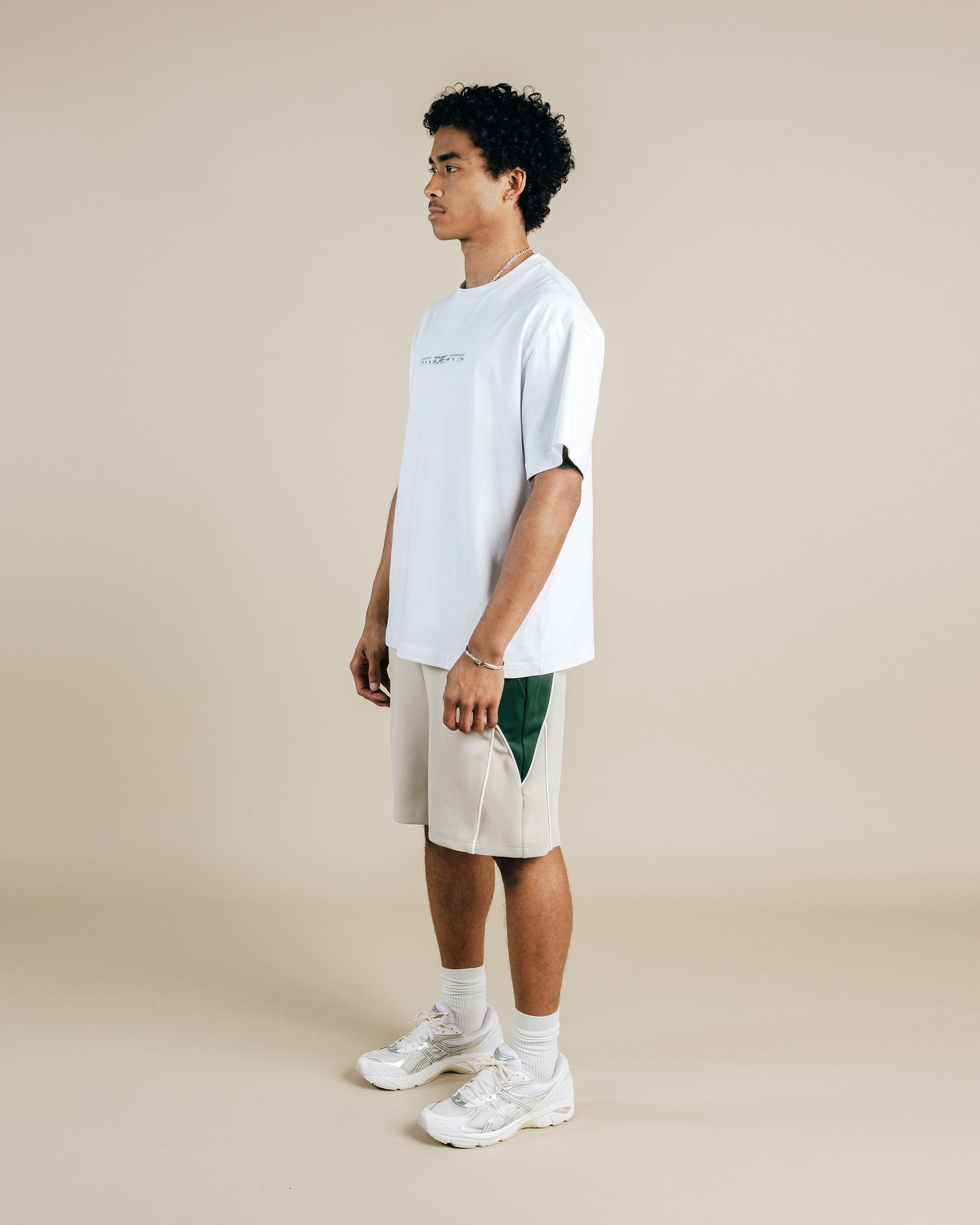 Person wearing a white t-shirt and beige shorts on a beige background