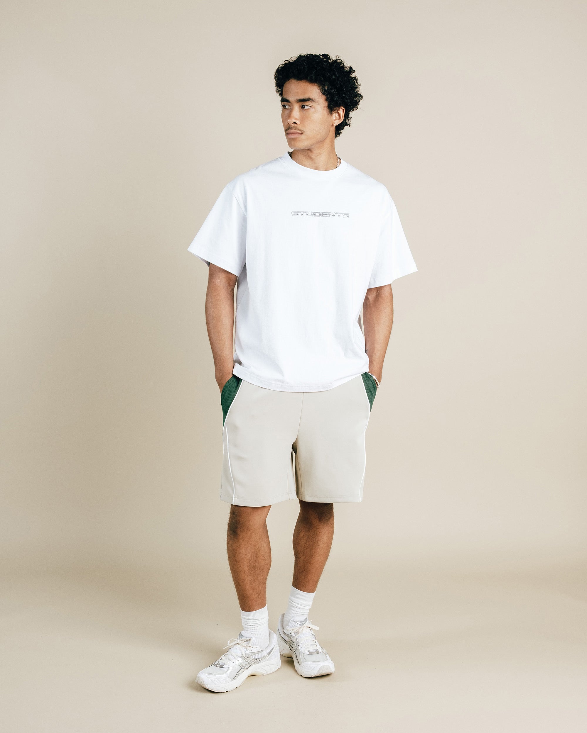 Person wearing a white t-shirt and beige shorts on a plain background