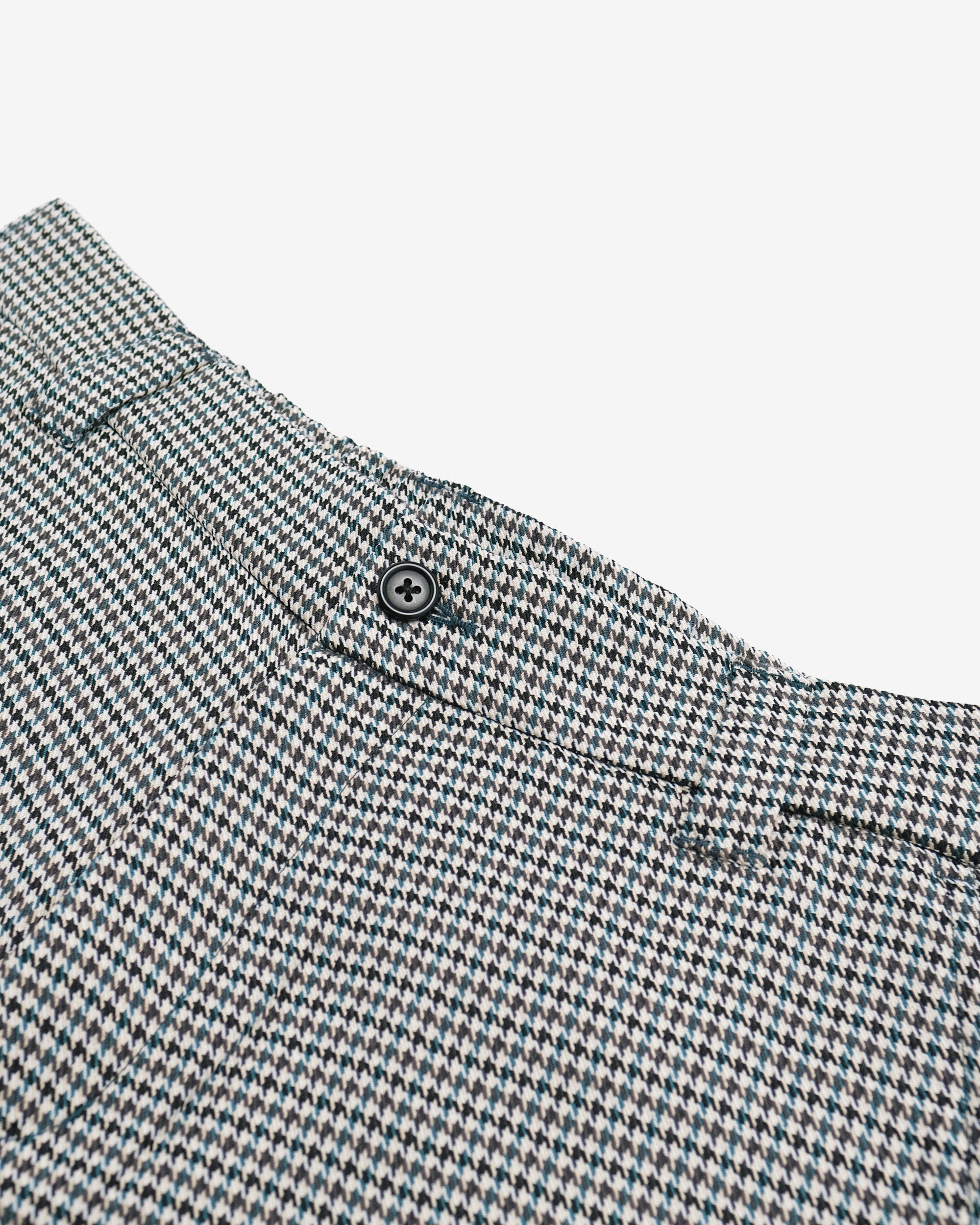Close-up of a houndstooth patterned fabric with a button on a white background