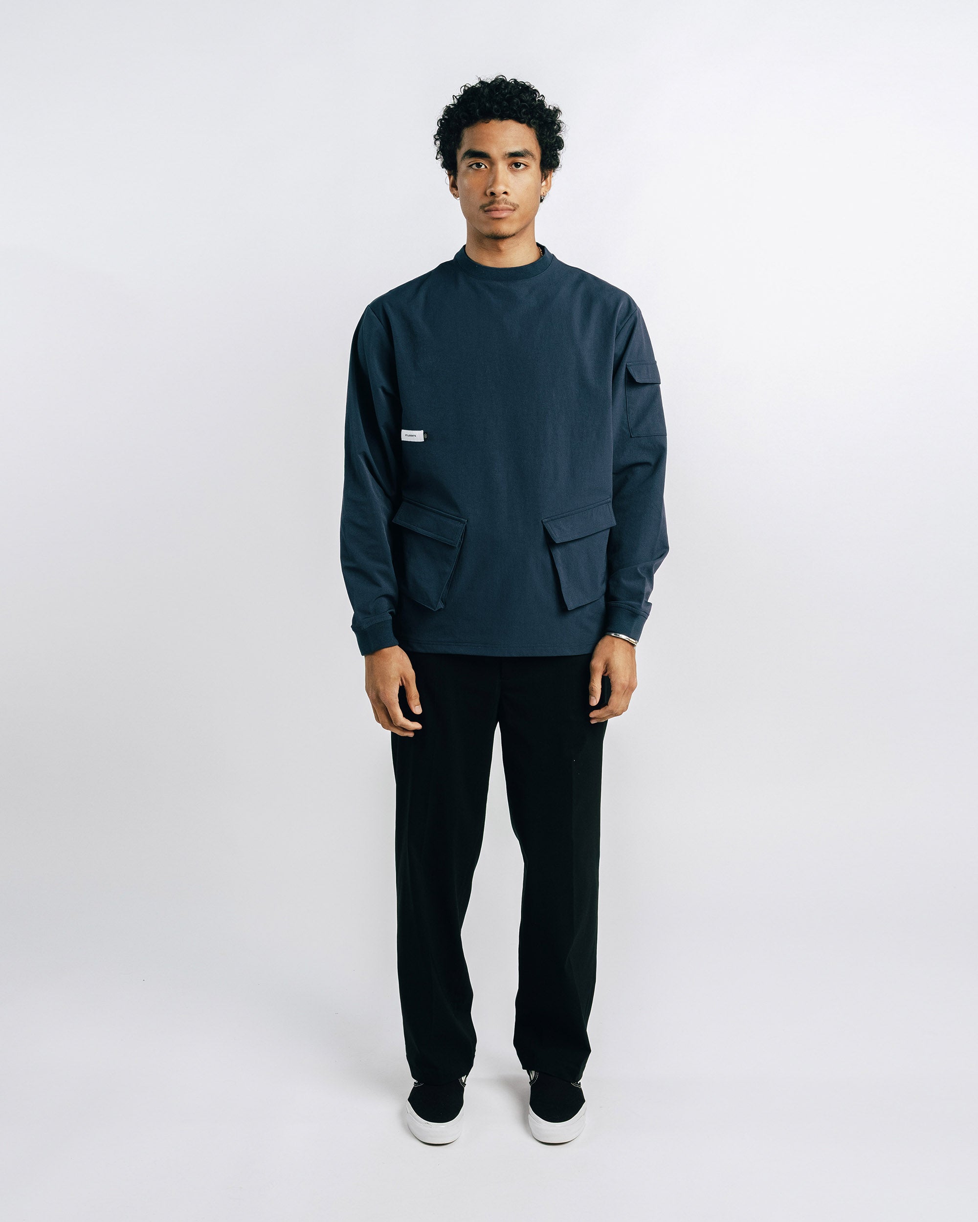 Person wearing a dark blue sweater and black pants on a white background