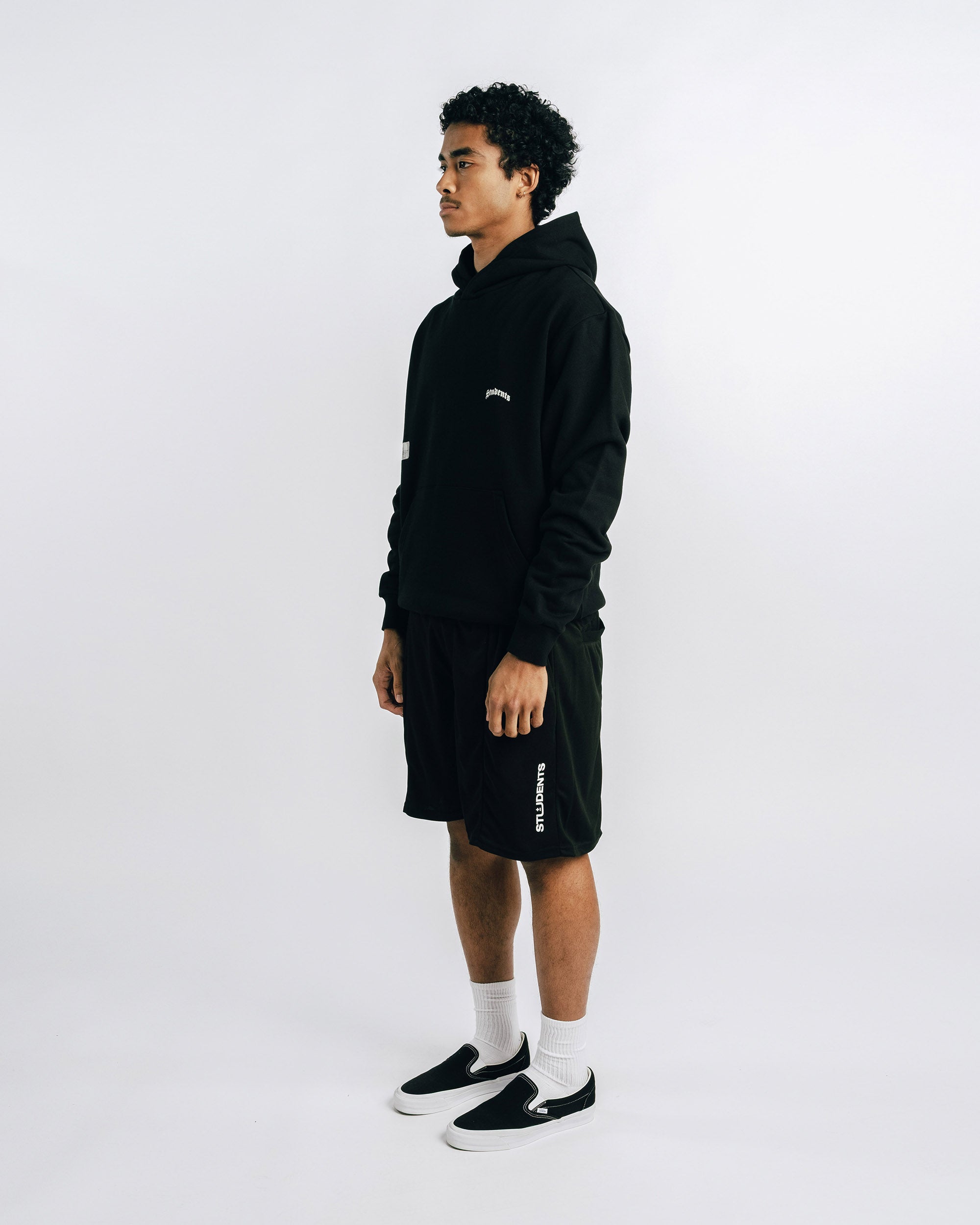 Person wearing a black outfit with visible branding on a white background