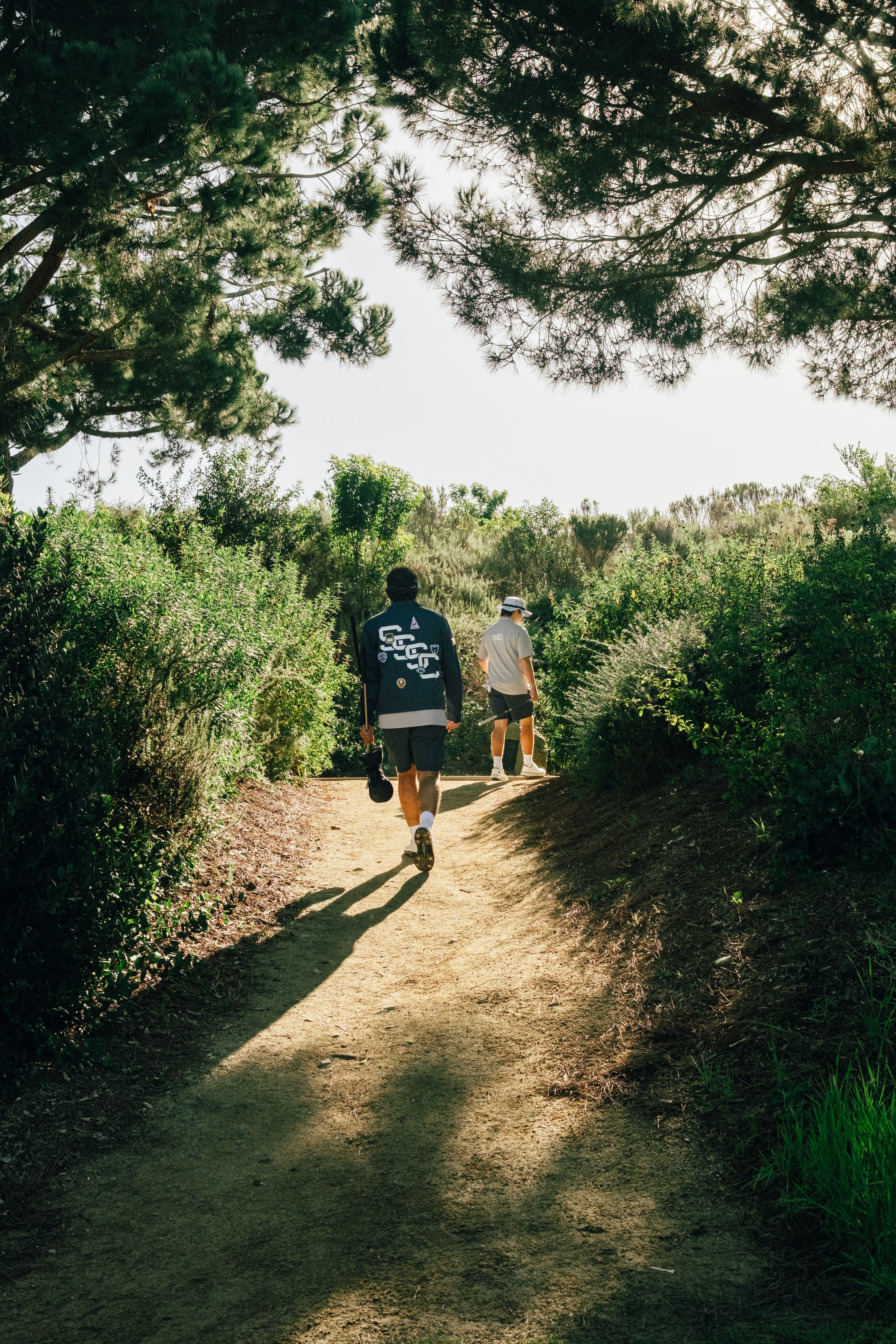 Two people walking on a dirt path through a forest