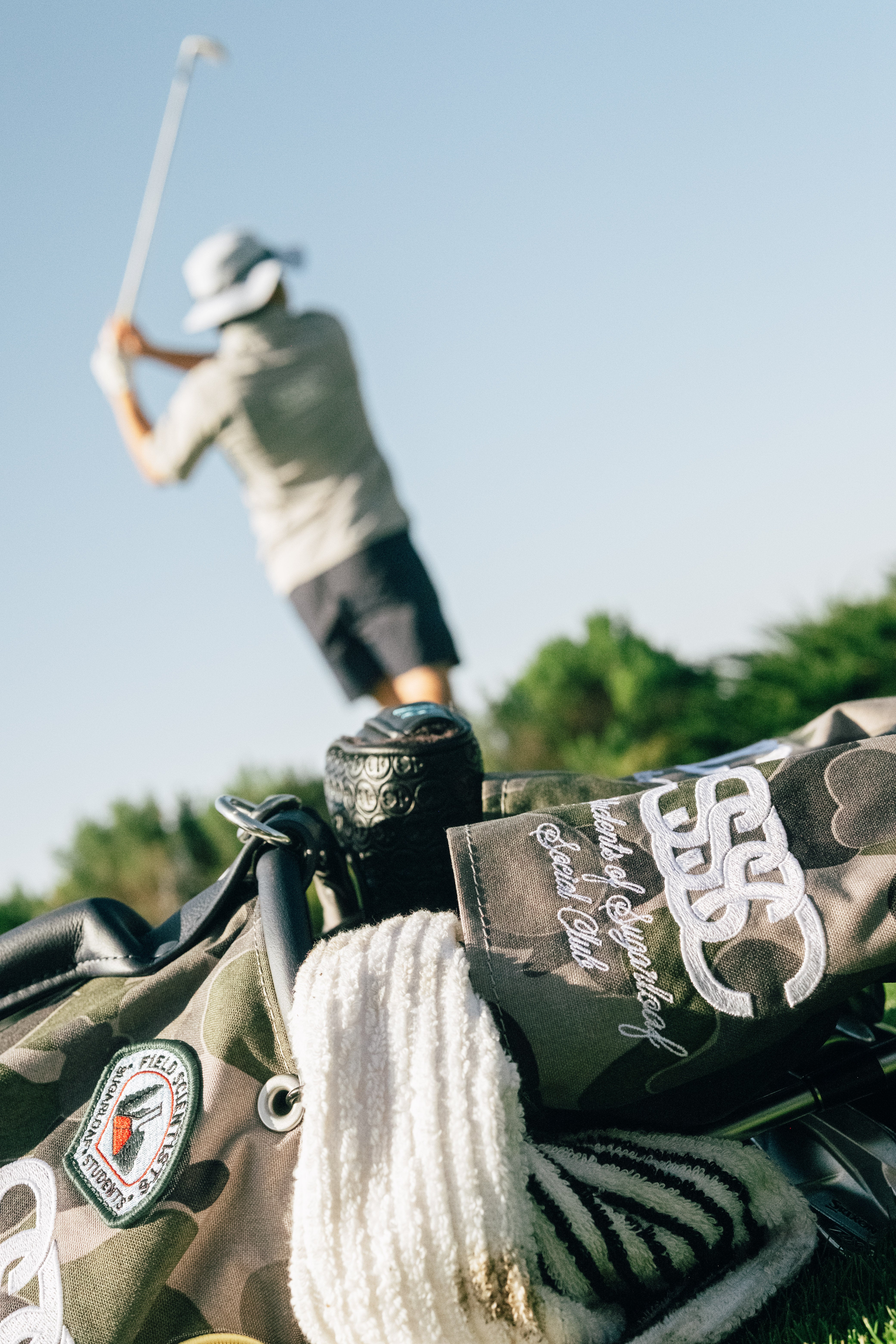 Golf bag with clubs and a golf club in use on a golf course