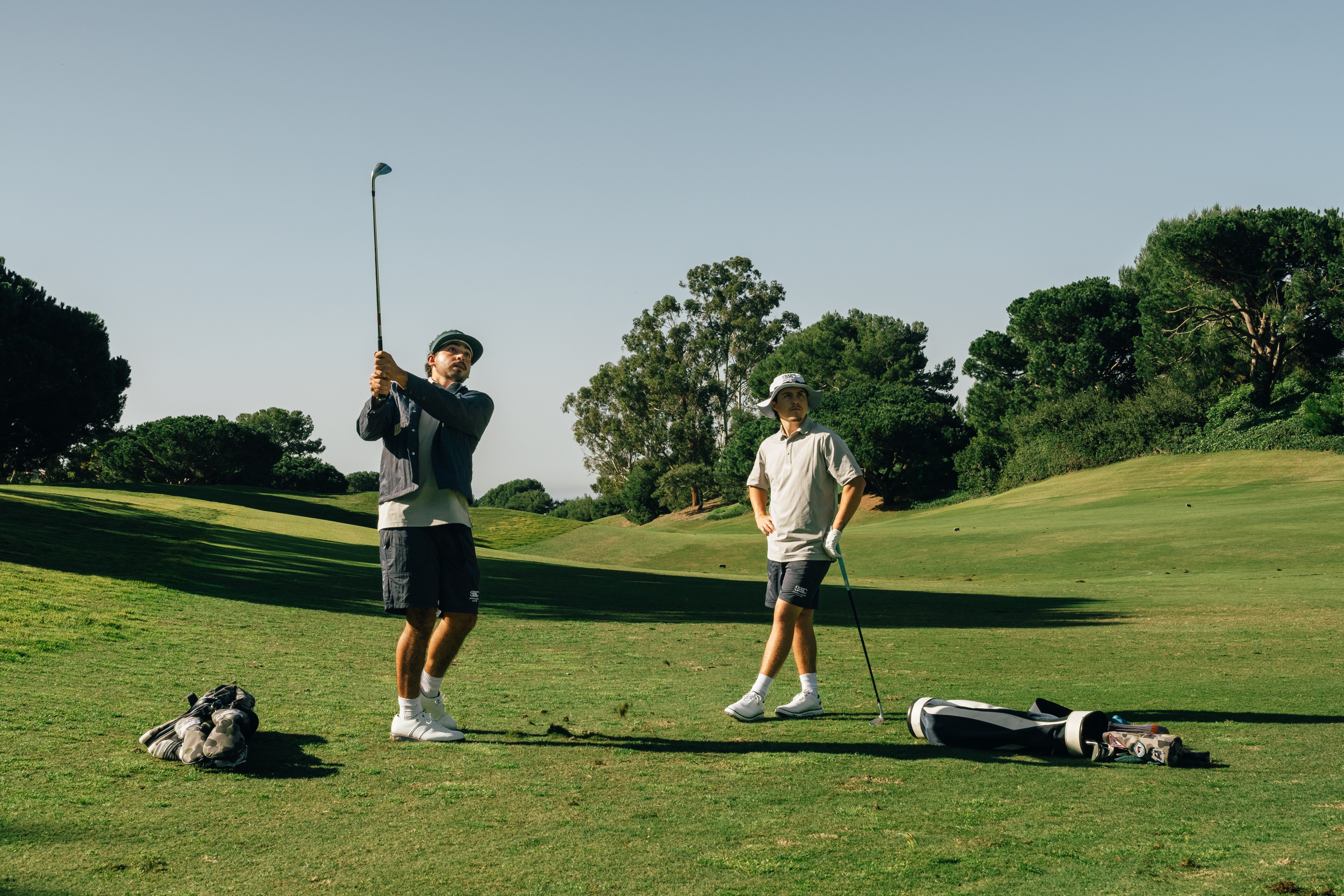 Two golfers on a green course with trees in the background