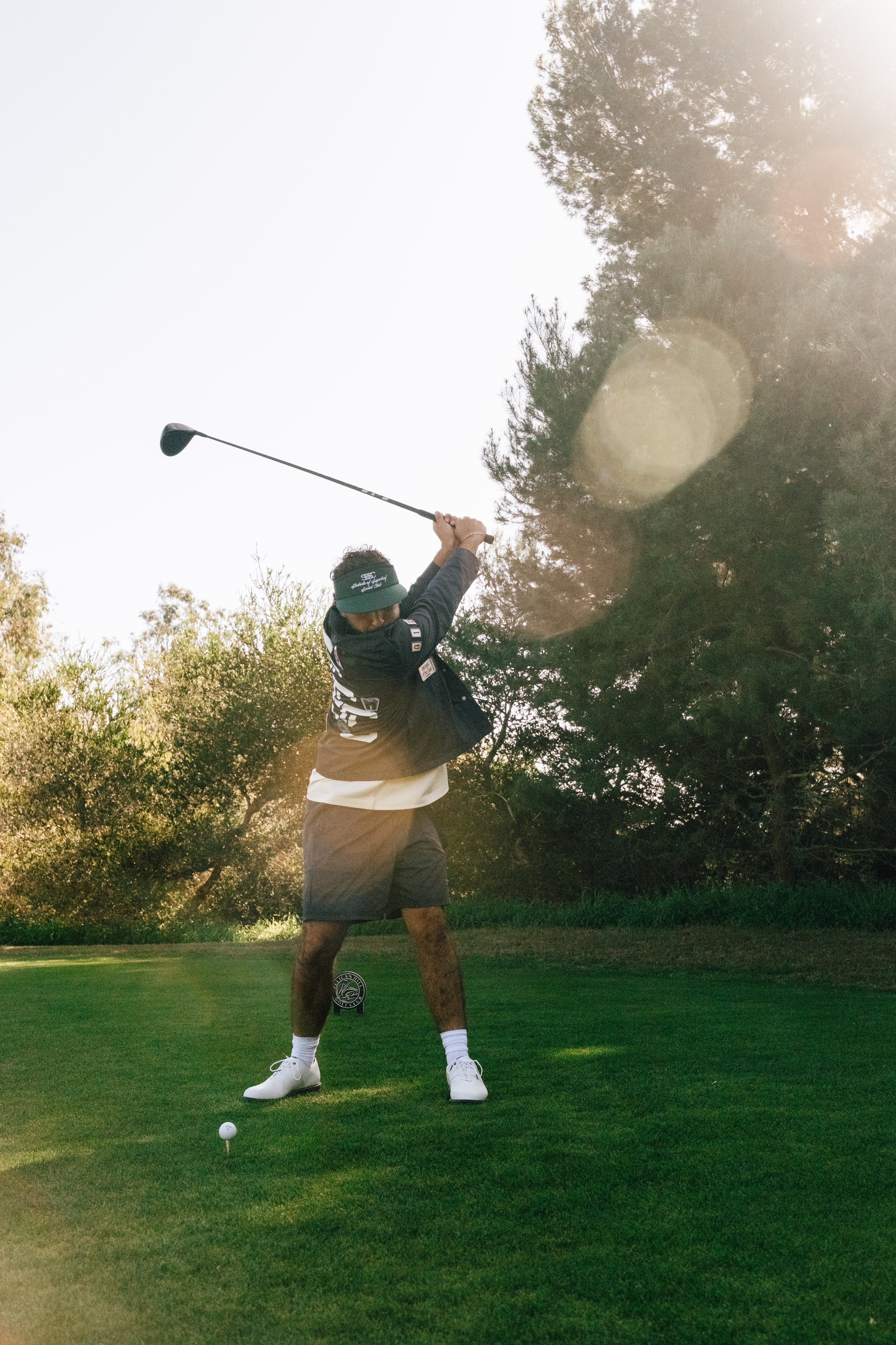 Person playing golf on a green course with trees in the background