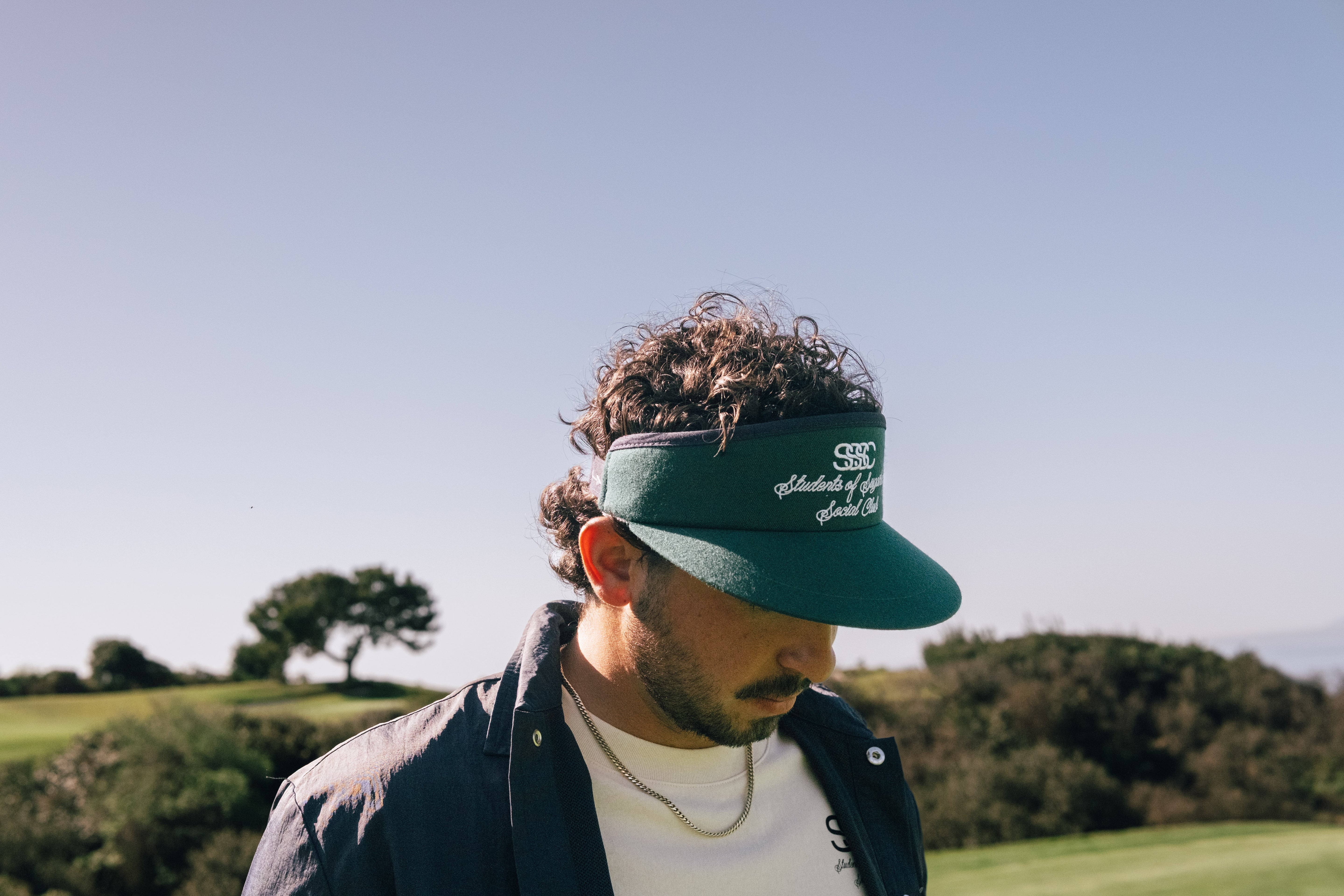 Man wearing a green visor with a logo on a golf course