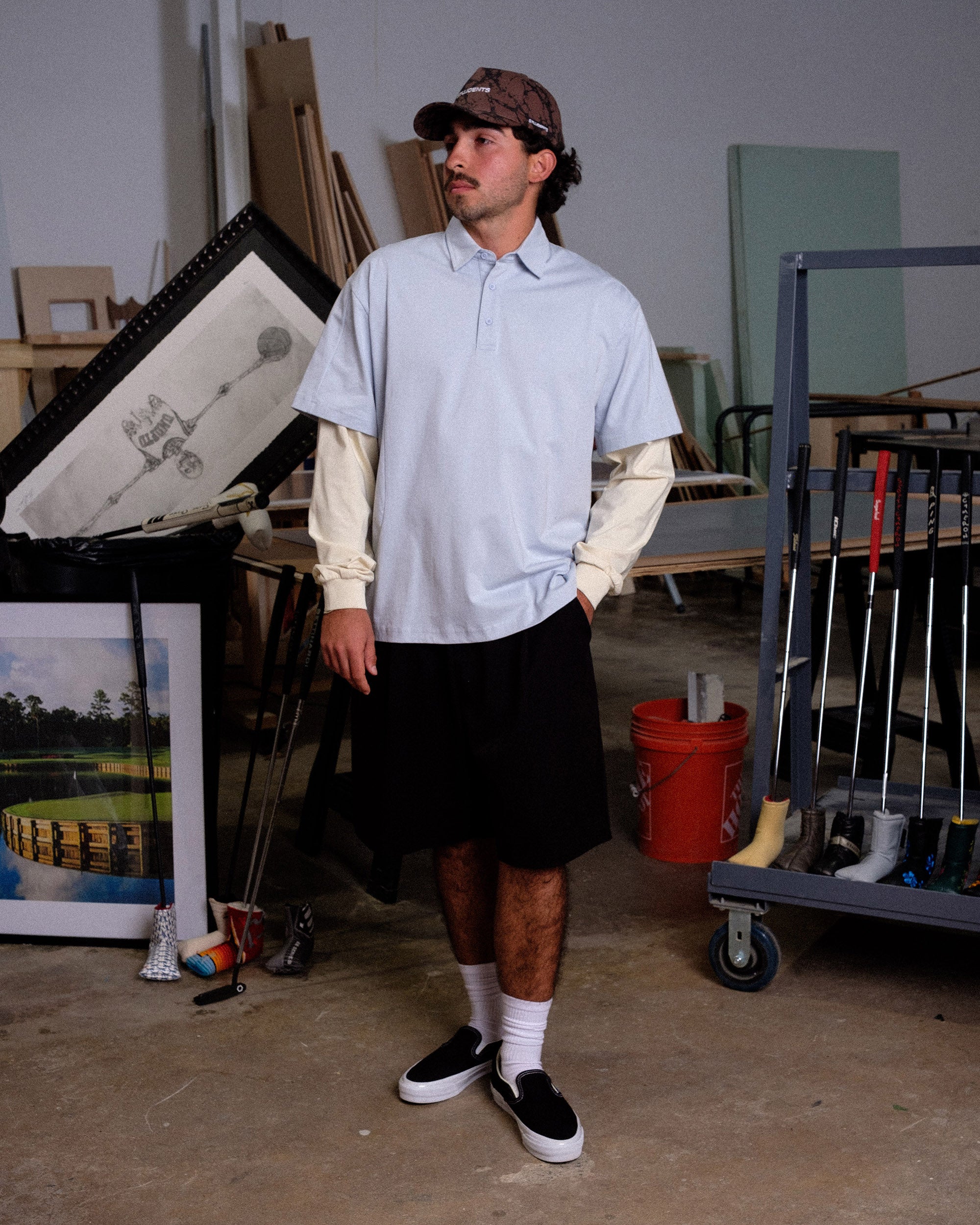 Person wearing a light blue shirt and black skirt in an indoor setting with art supplies and furniture.