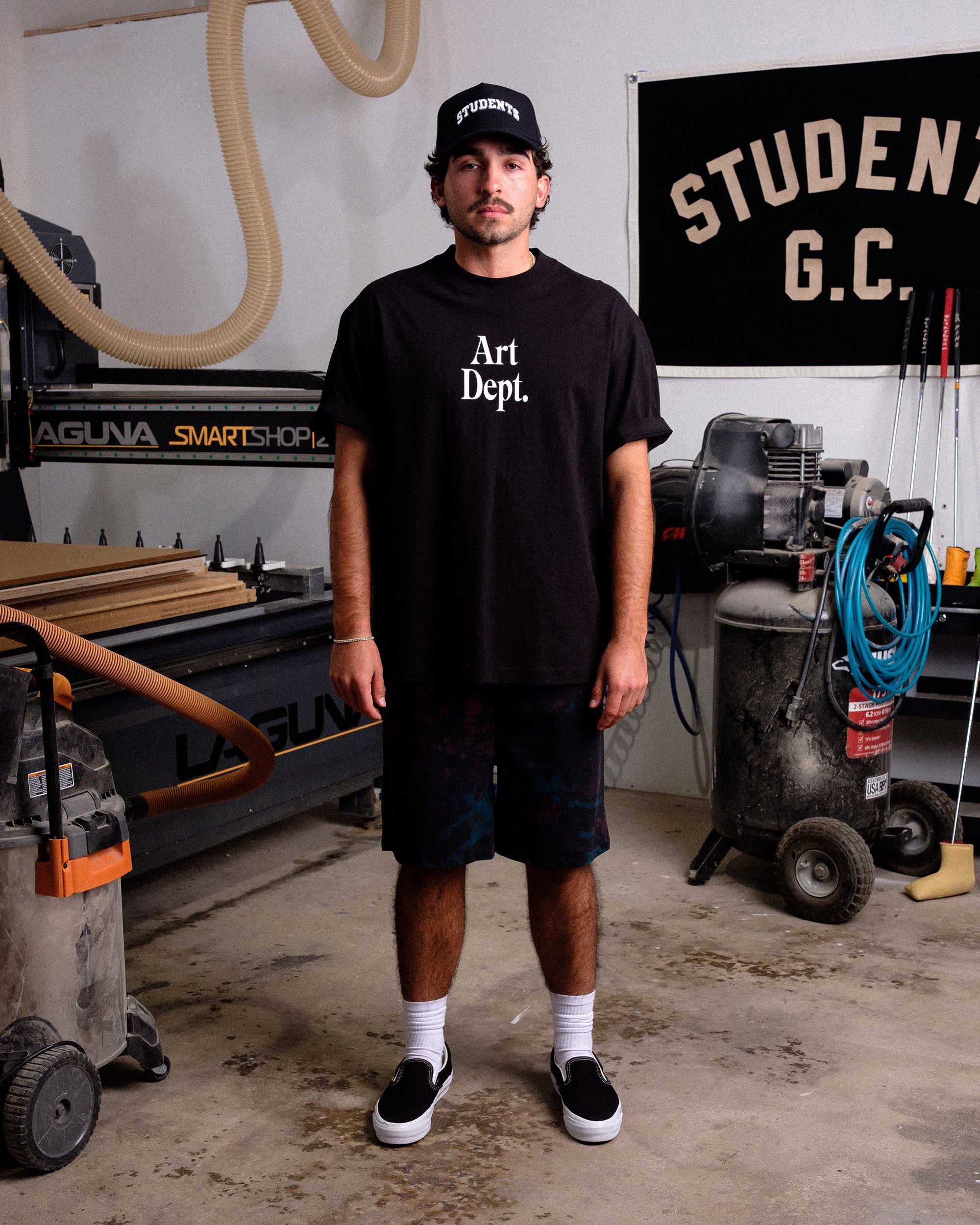 Person wearing a black 'Art Dept.' t-shirt in a workshop setting