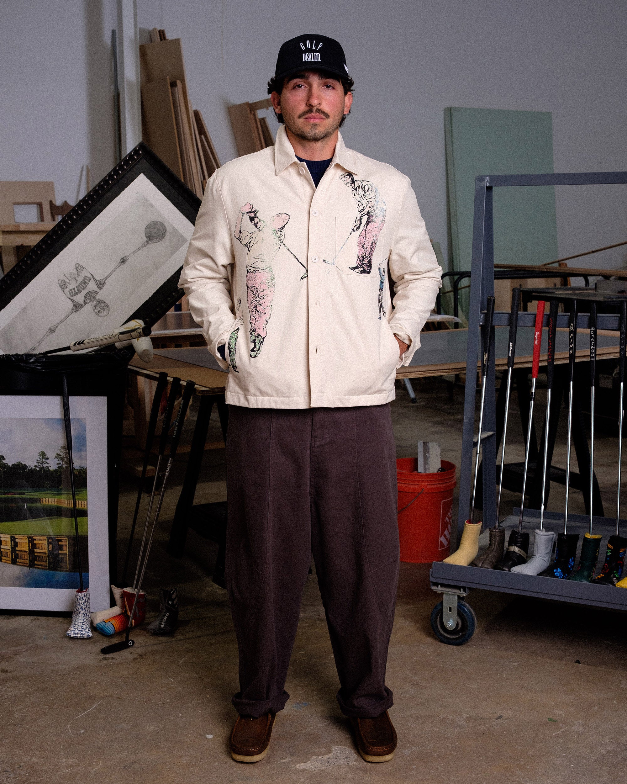 Man wearing a cream jacket with graphic designs in an indoor setting