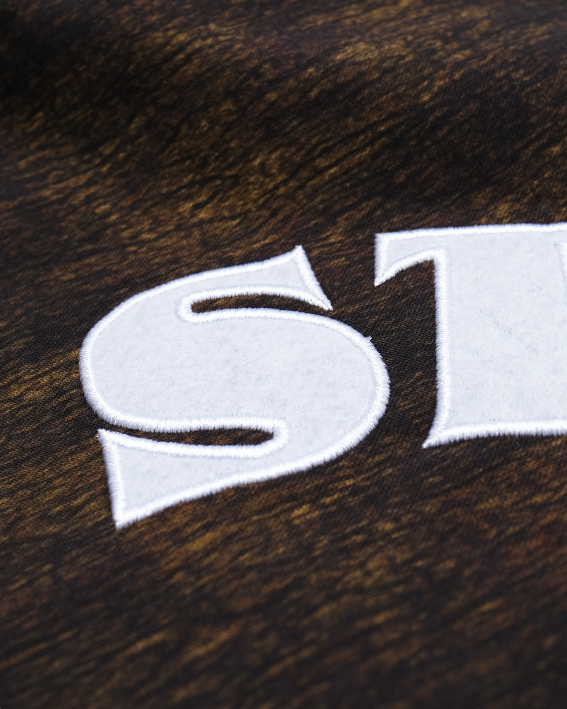 White 'ST' logo on a brown textured background