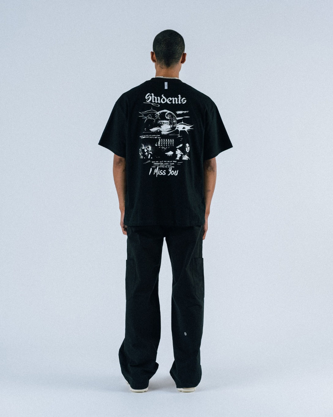 Person wearing a black t-shirt with graphic design on the back against a white background