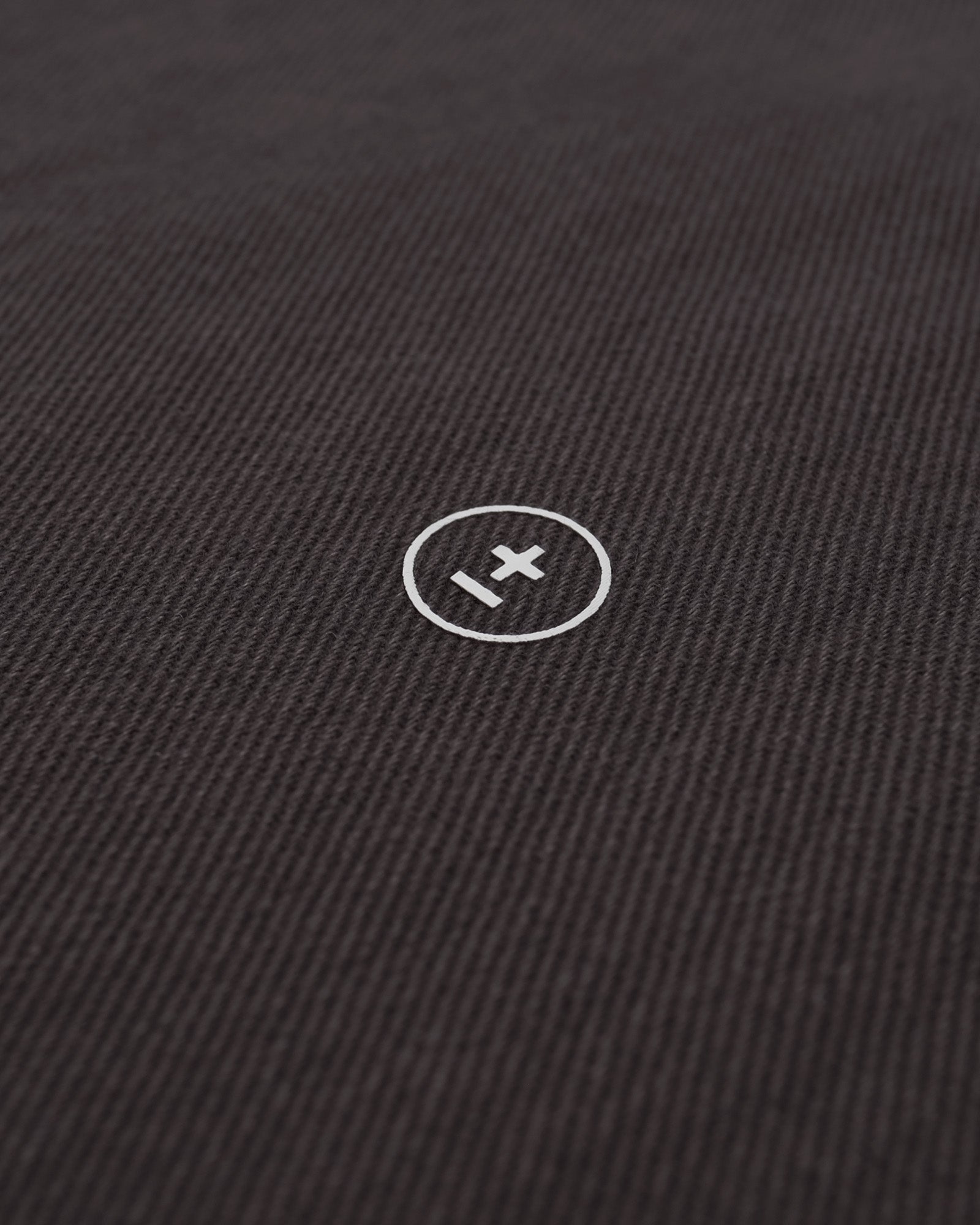 Close-up of a black fabric surface with a white logo in the center.