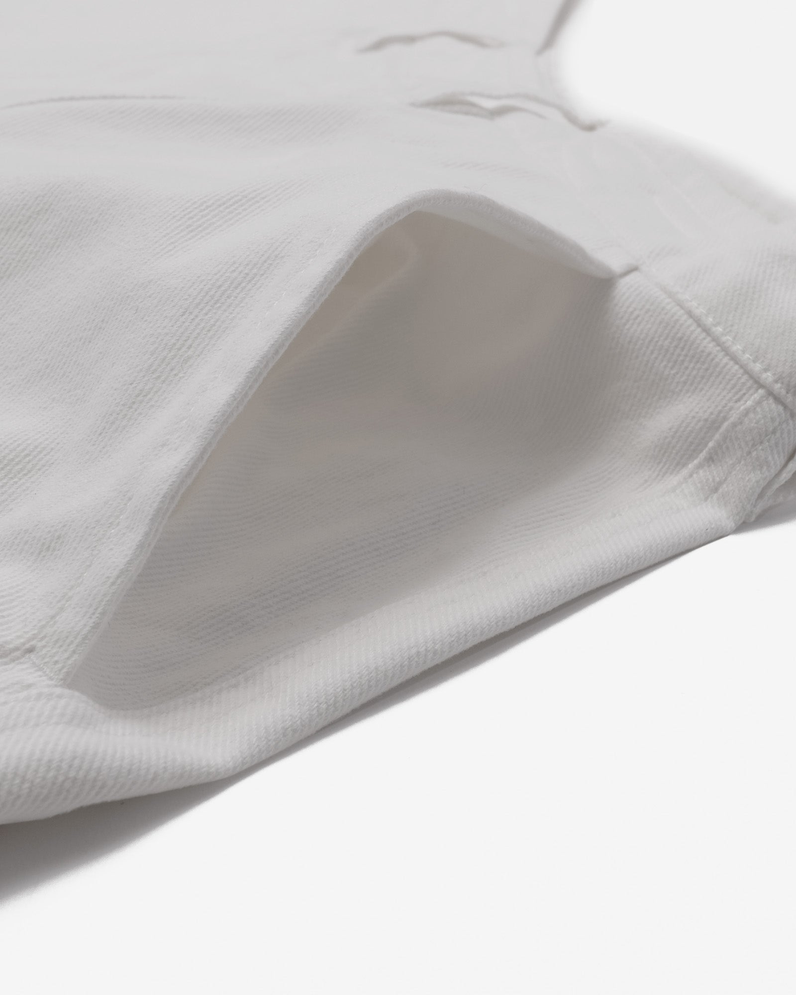 Close-up of a white garment with a pocket on a light gray background