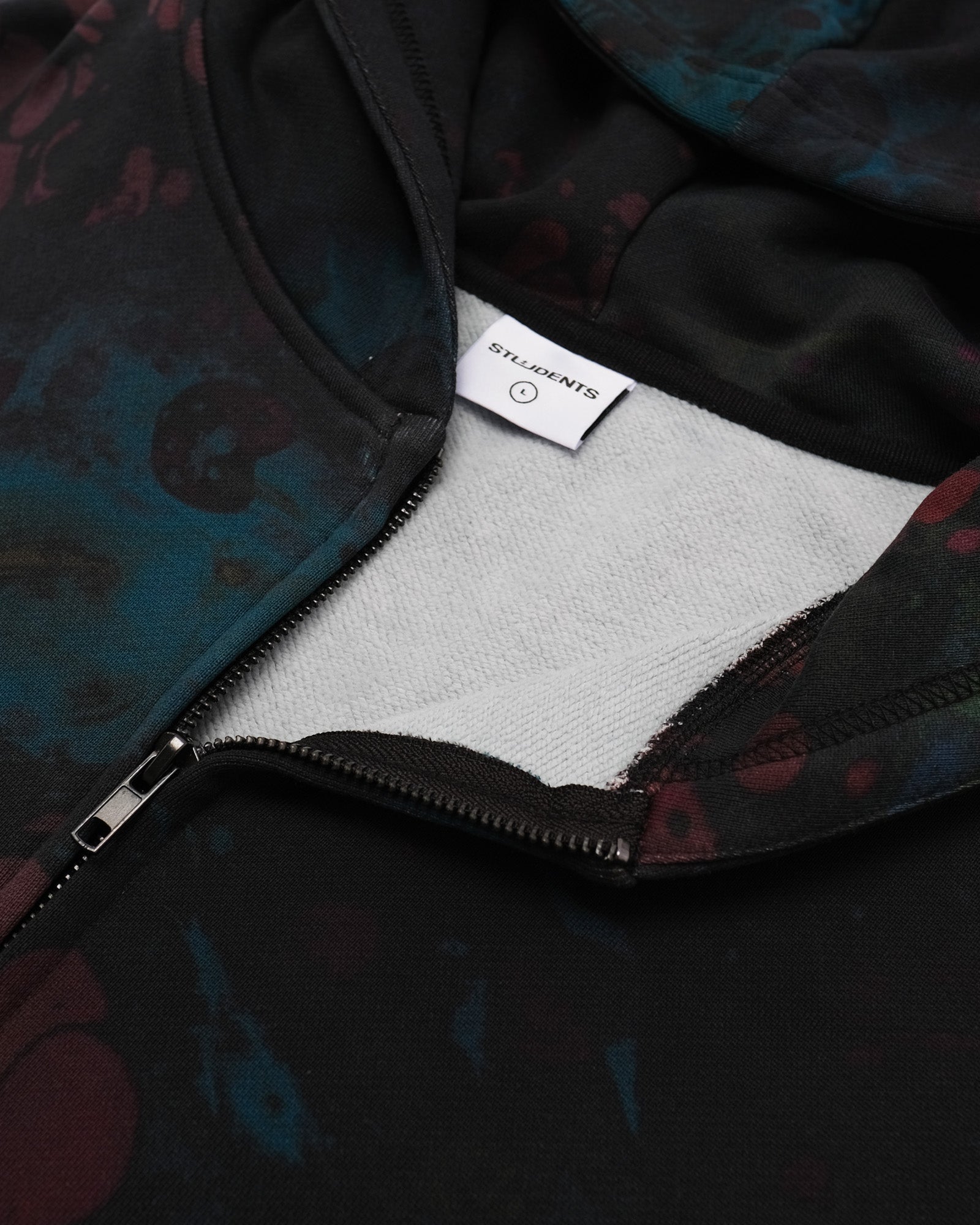 Close-up of a jacket with a brand label inside, showing a dark patterned fabric exterior.