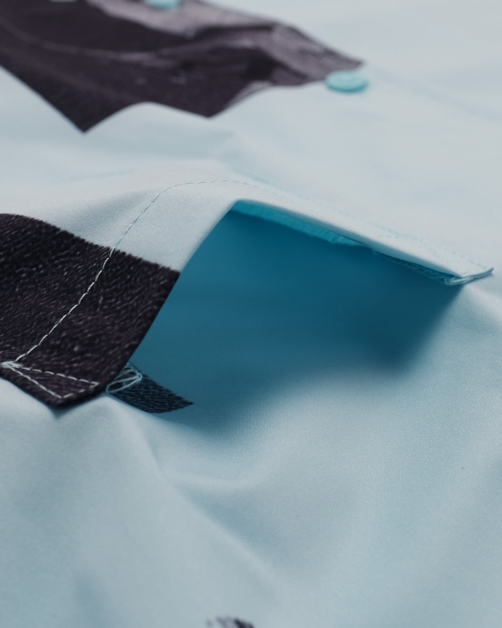 Close-up of a light blue shirt with dark collar and button details.
