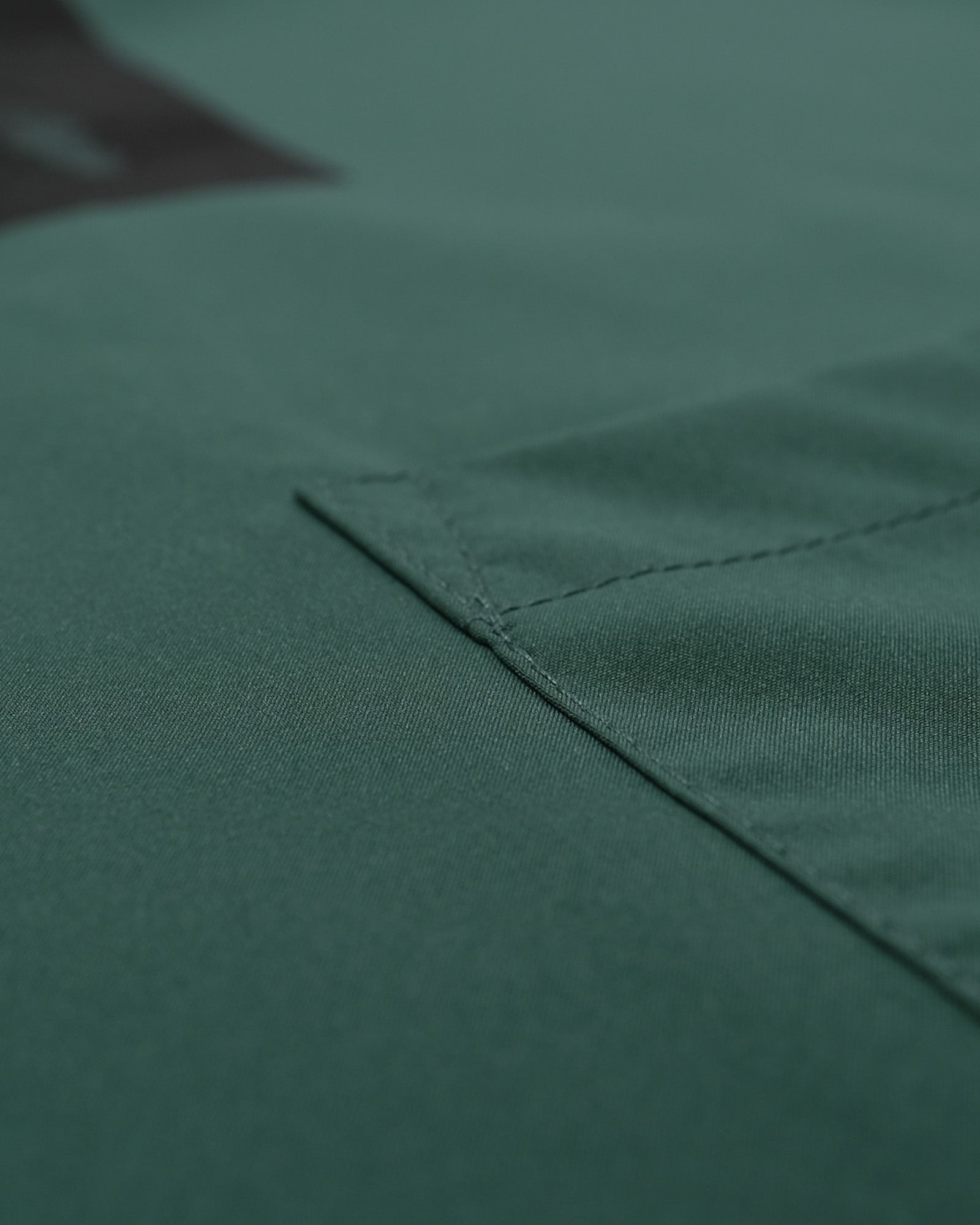 Close-up of a green fabric texture with a visible seam.