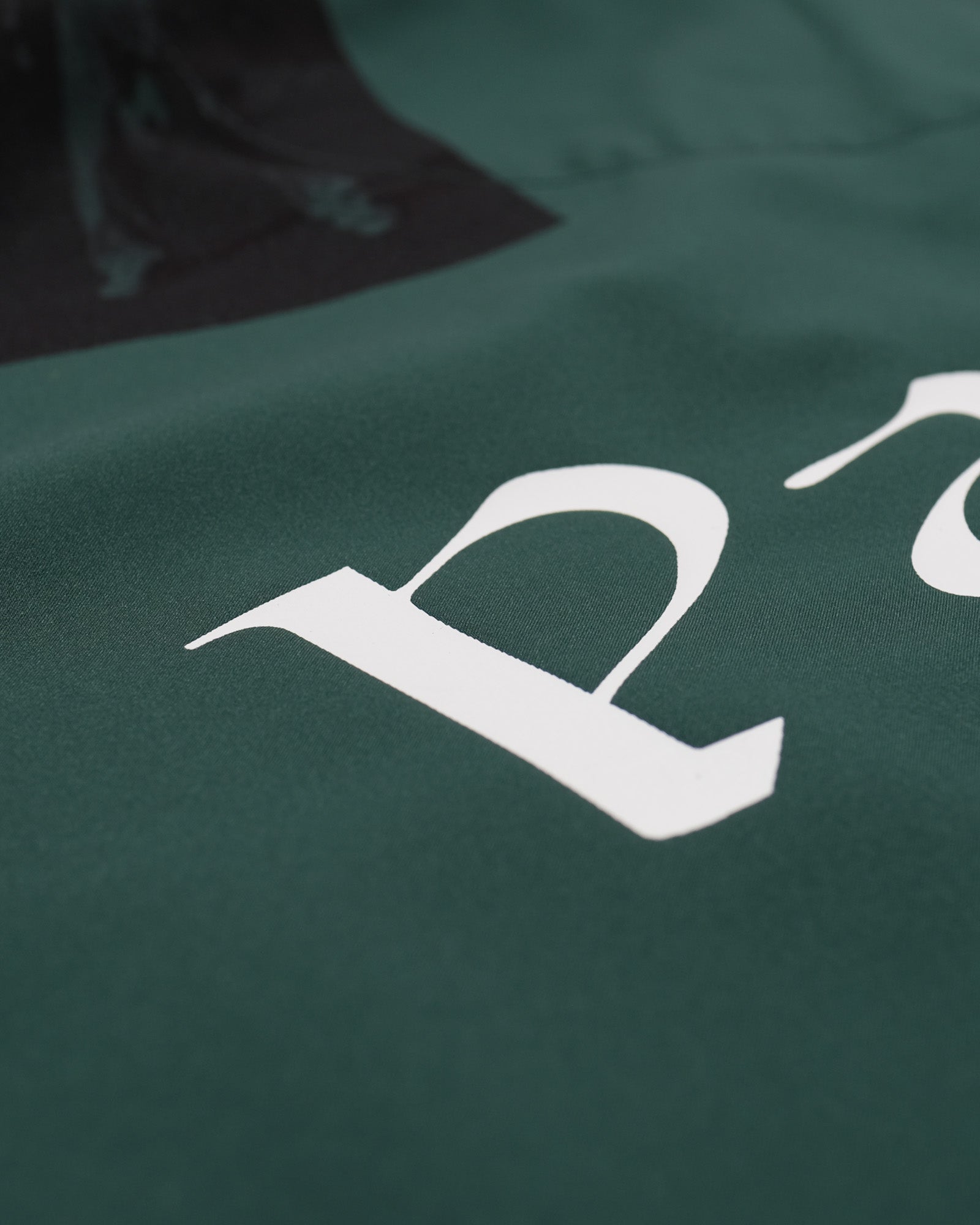 Green shirt with a white logo on a dark background