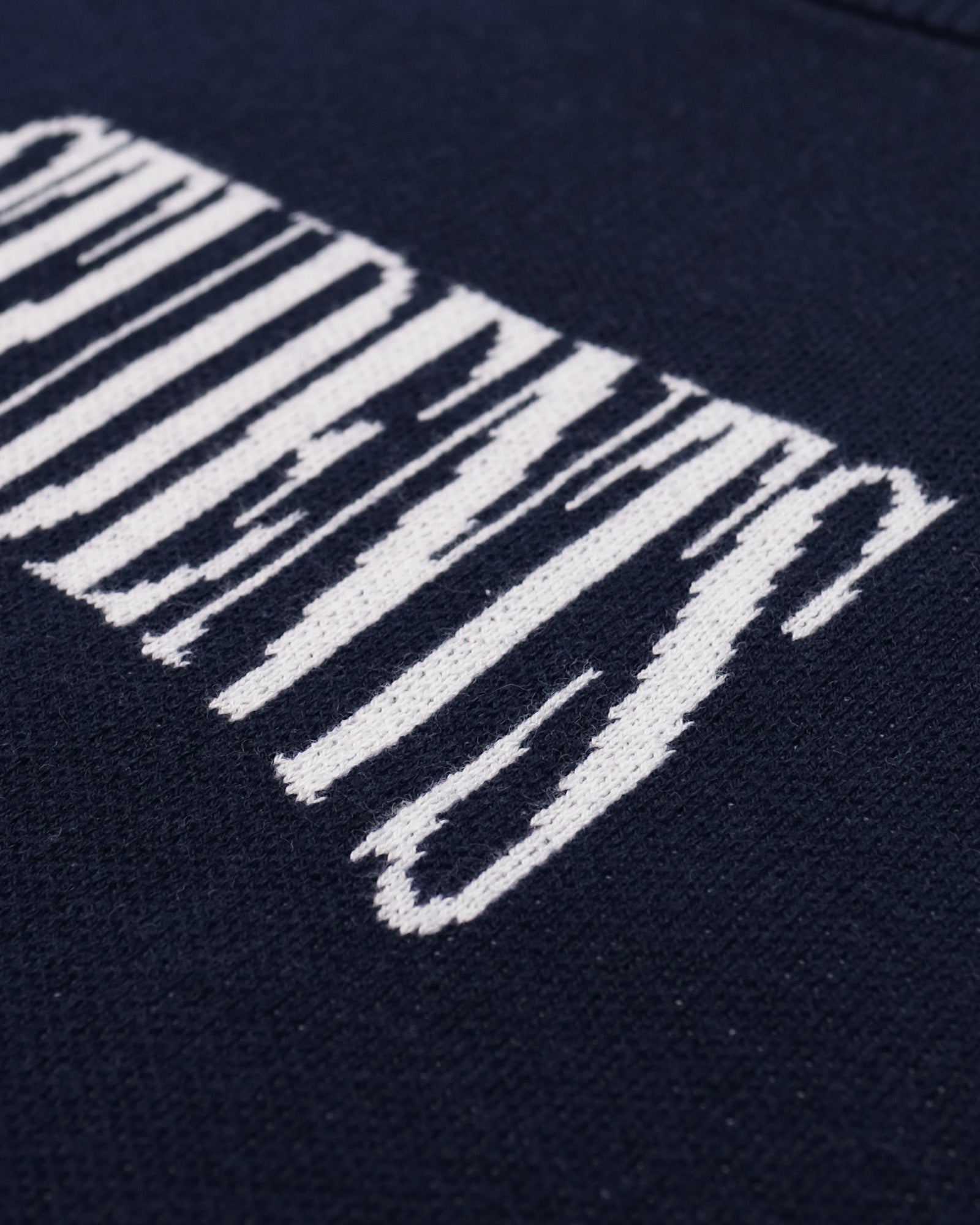 Close-up of a navy blue fabric with white embroidered text.