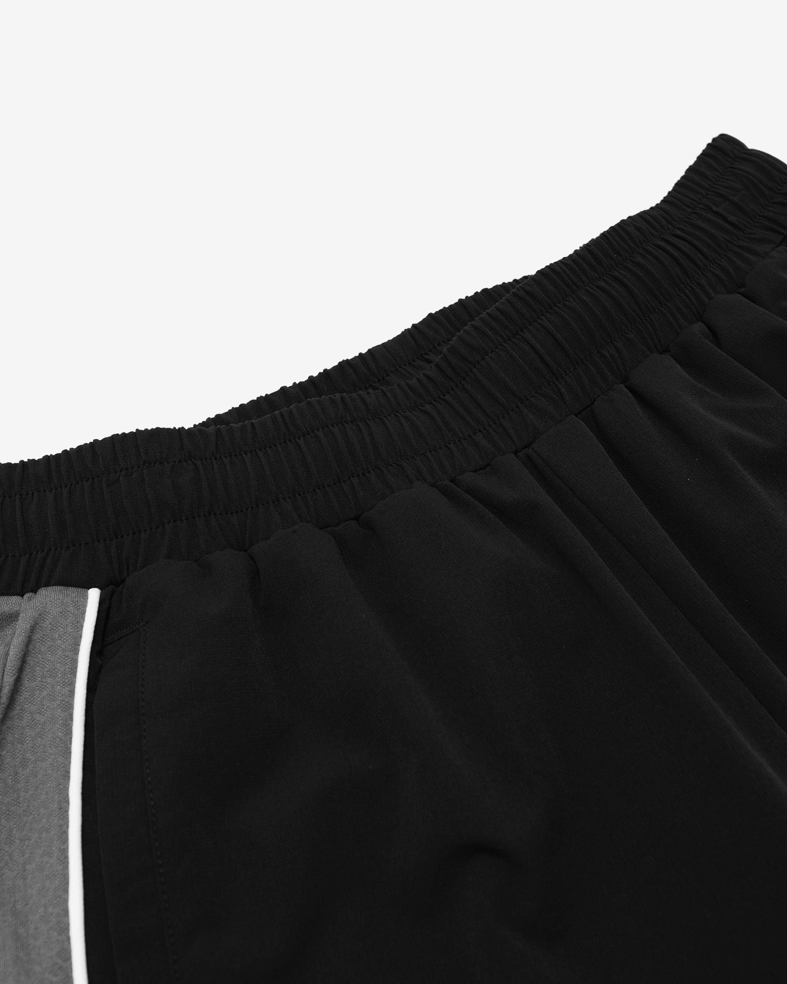 Close-up of black athletic shorts with a white stripe on a light gray background