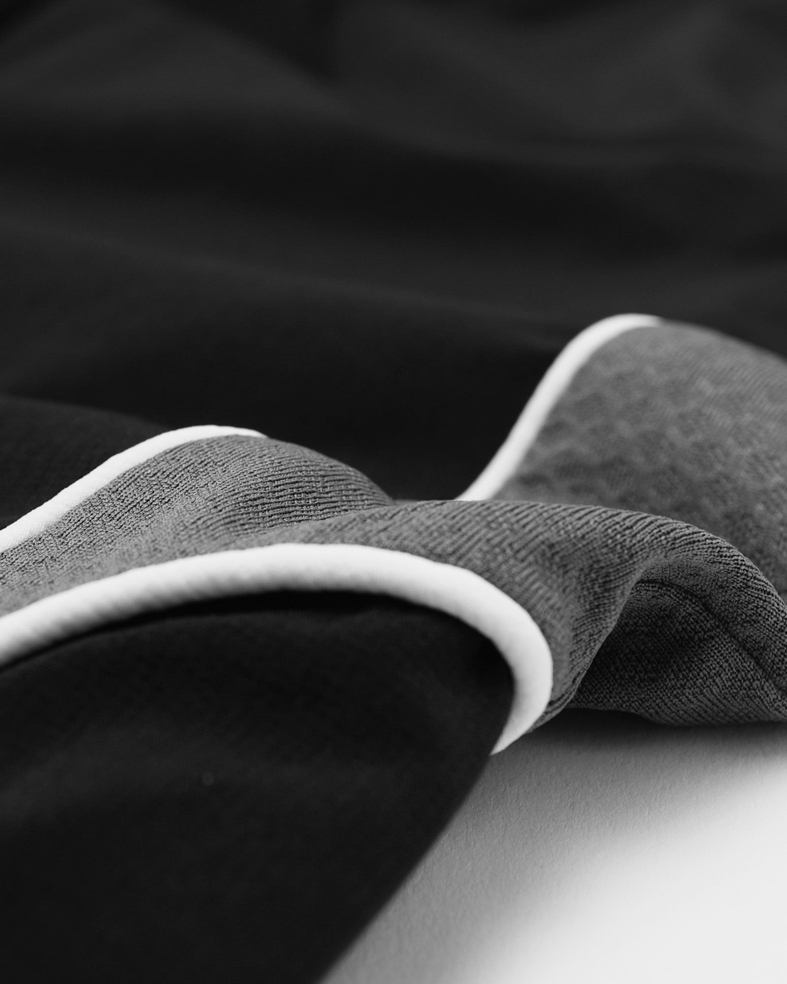 Close-up of black fabric with white trim on a dark background