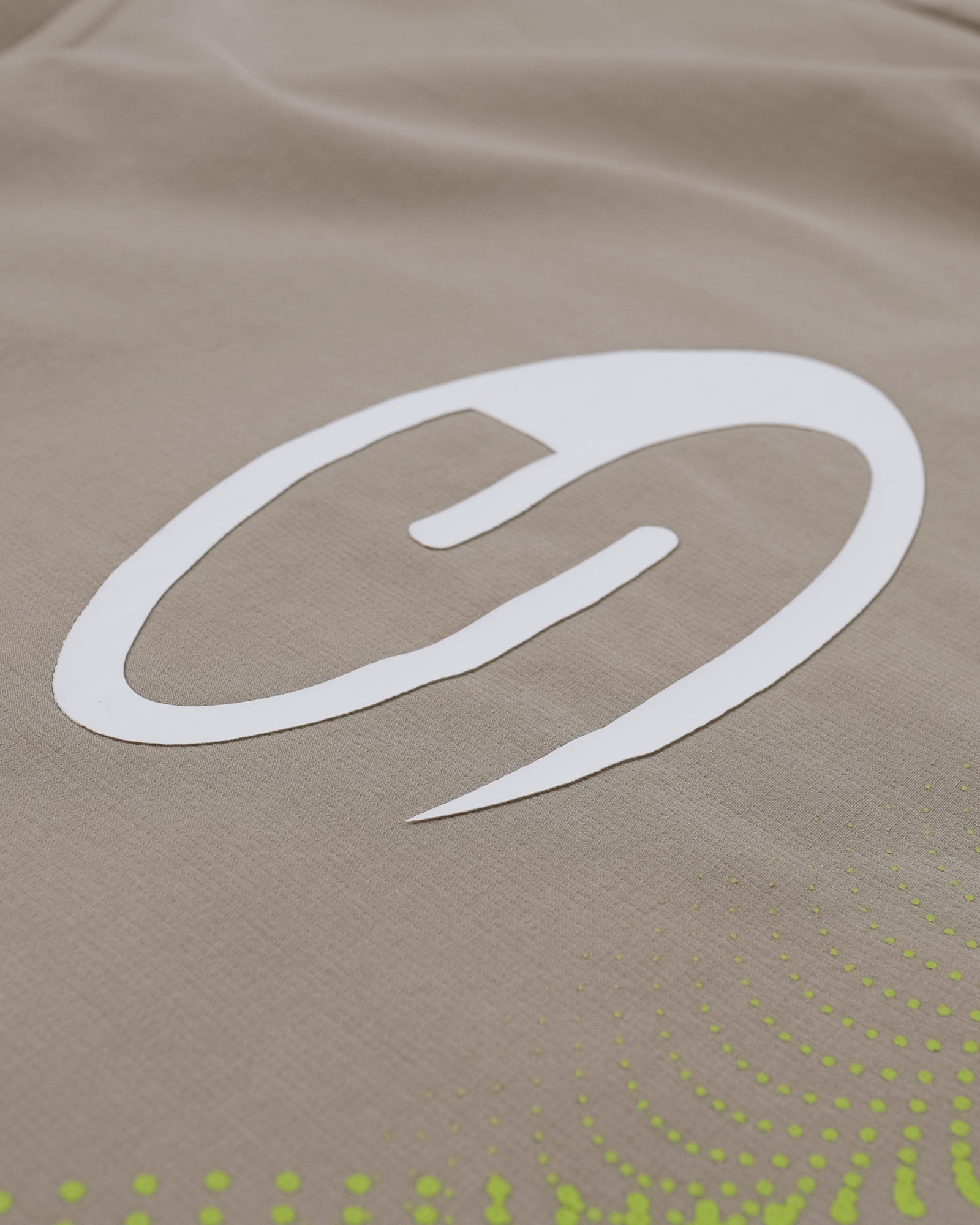 Close-up of a logo on a beige fabric surface with green patterns.