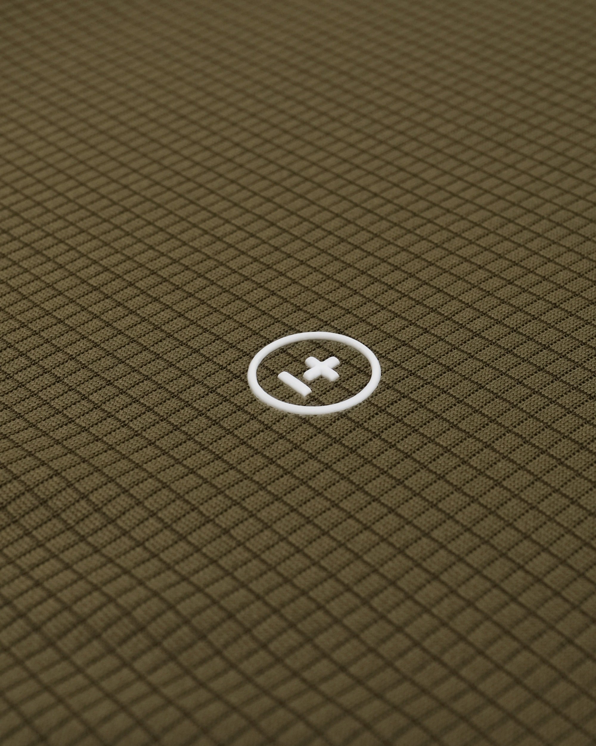 Close-up of a textured green fabric with a white logo in the center.