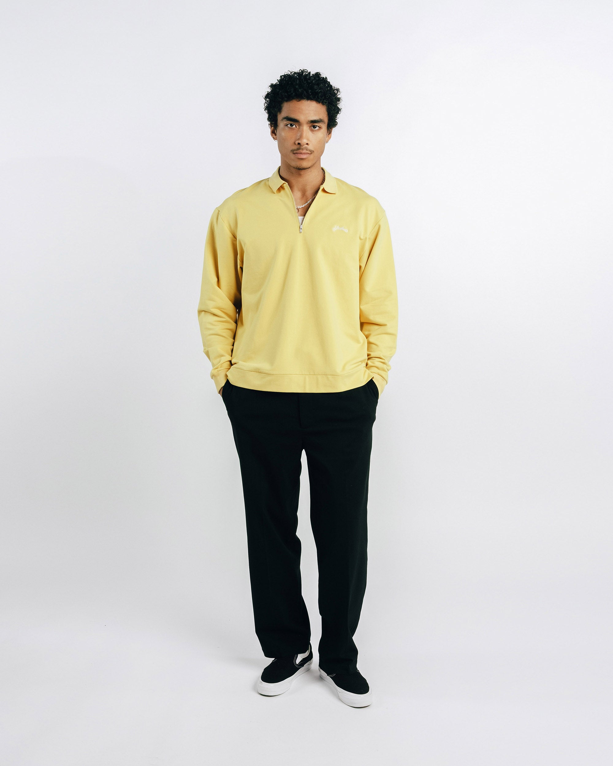 Man wearing a yellow shirt and black pants on a white background
