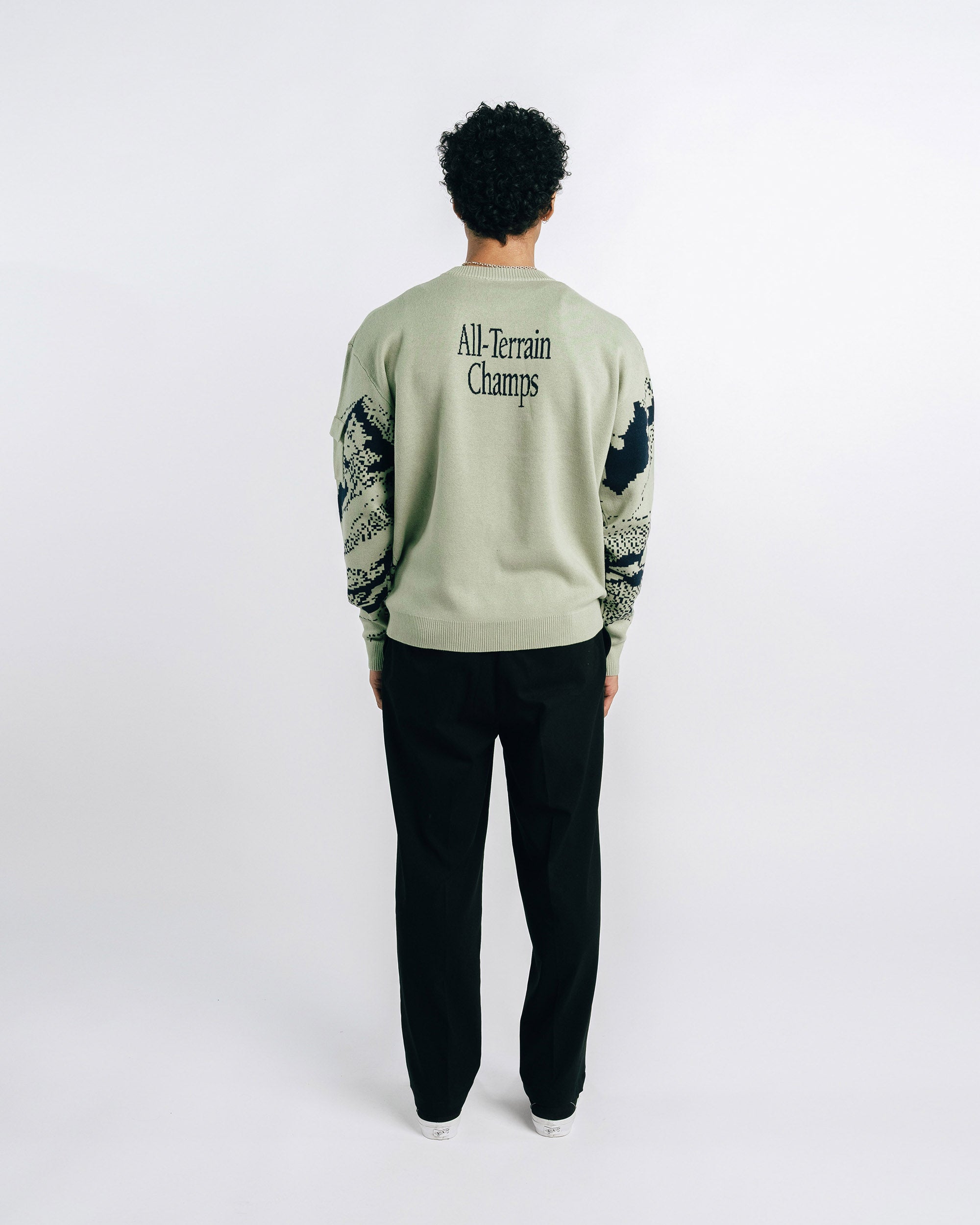 Green sweater with black mountain design on a white background