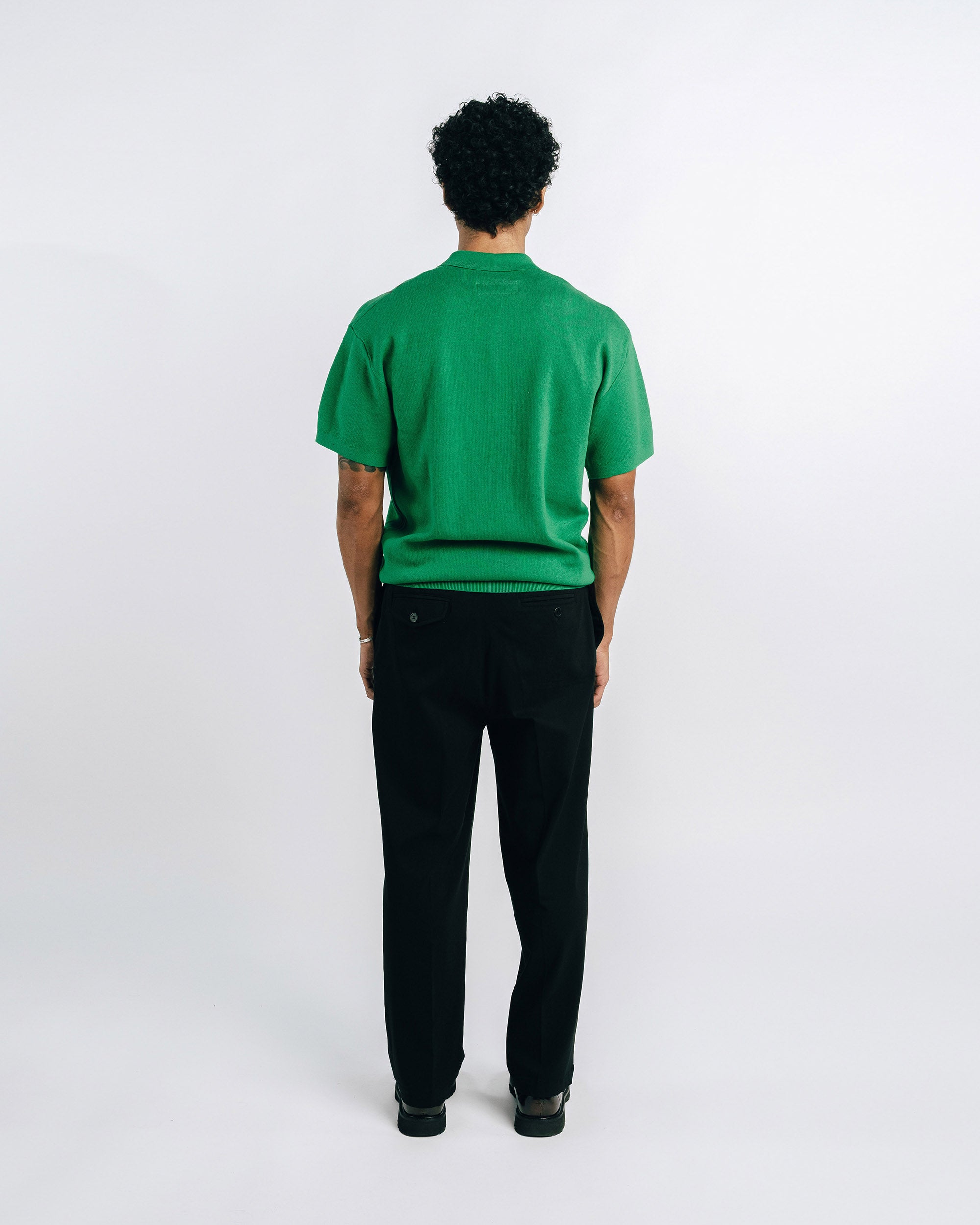 Person wearing a green shirt with suspenders on a white background