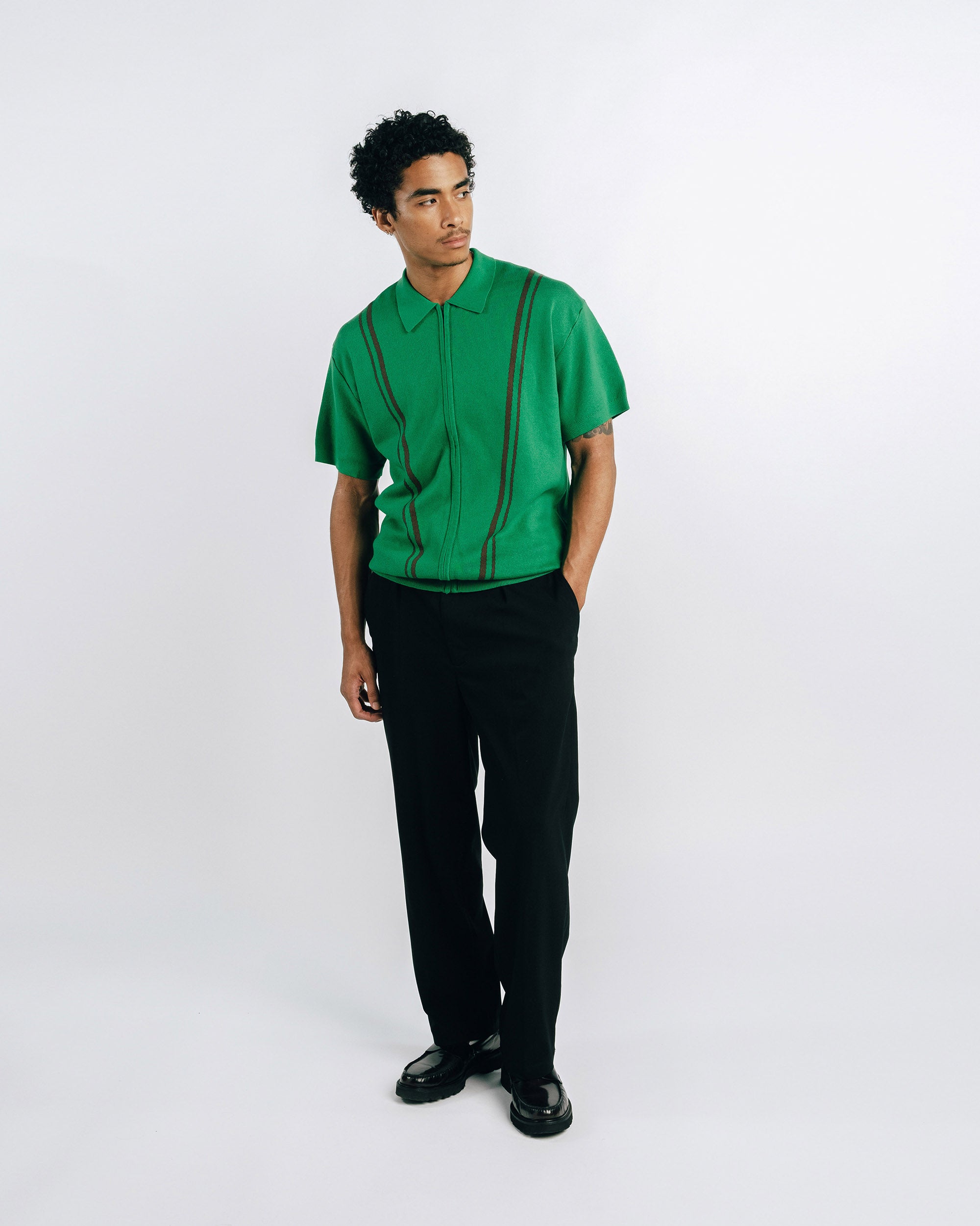 Person wearing a green shirt with black pants on a white background