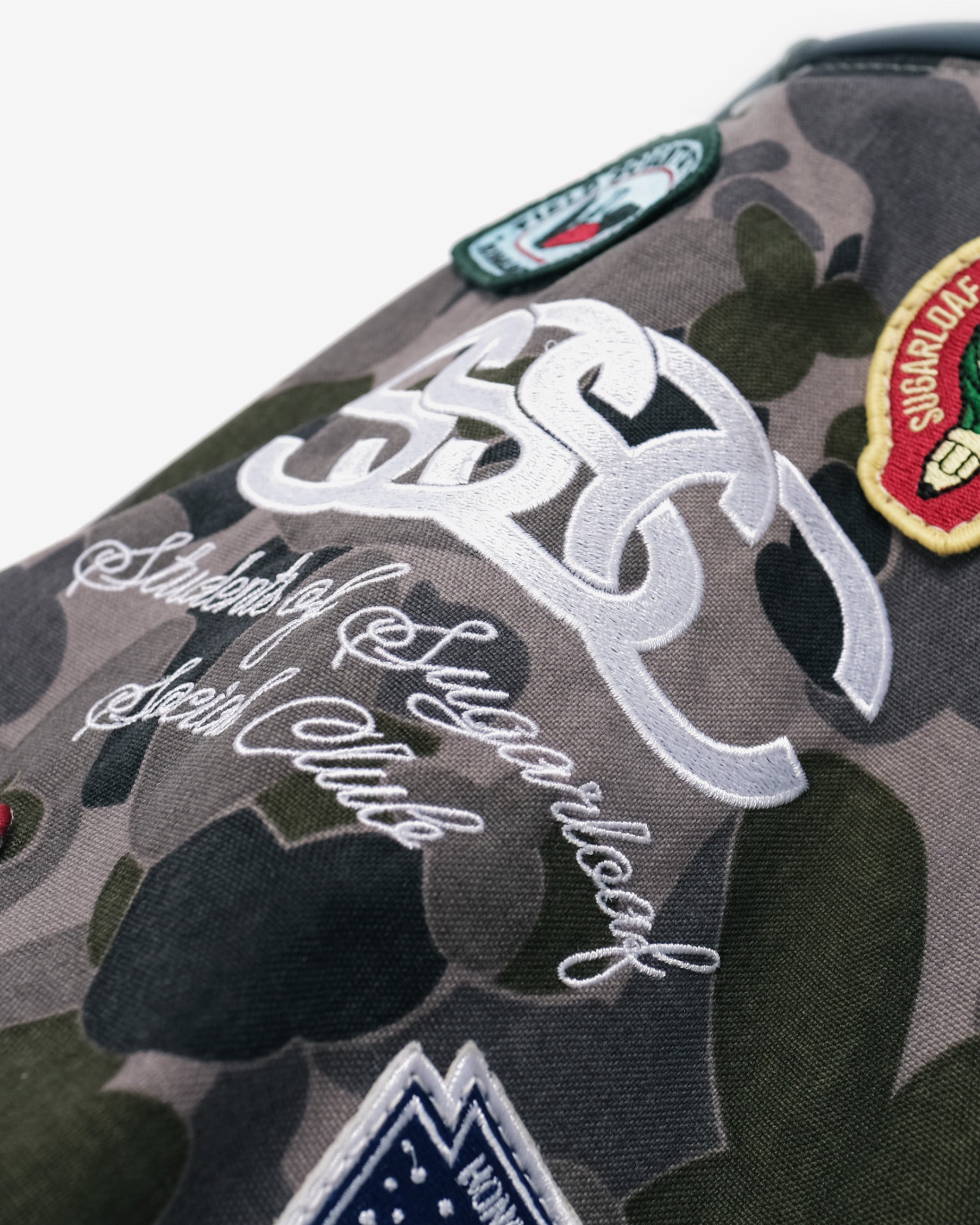 Camouflage golf bag with patches and branding on a white background