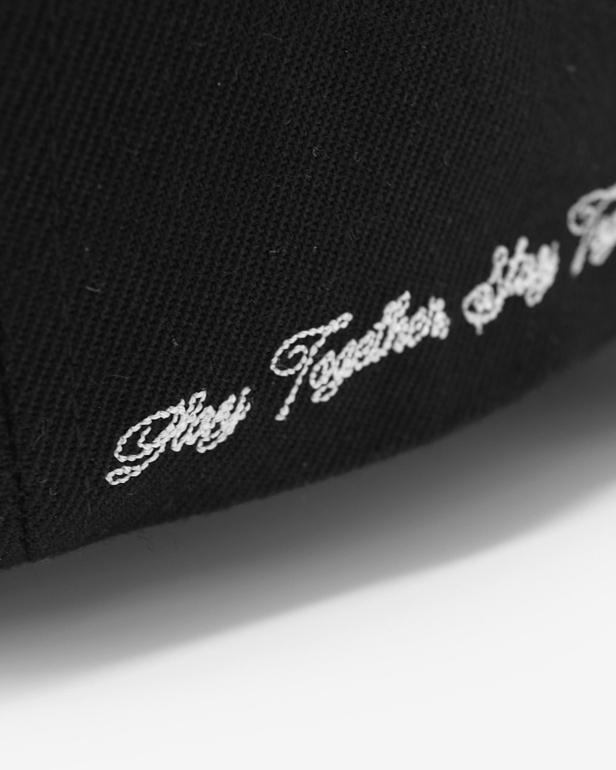 Black cap with white embroidered text on a white background