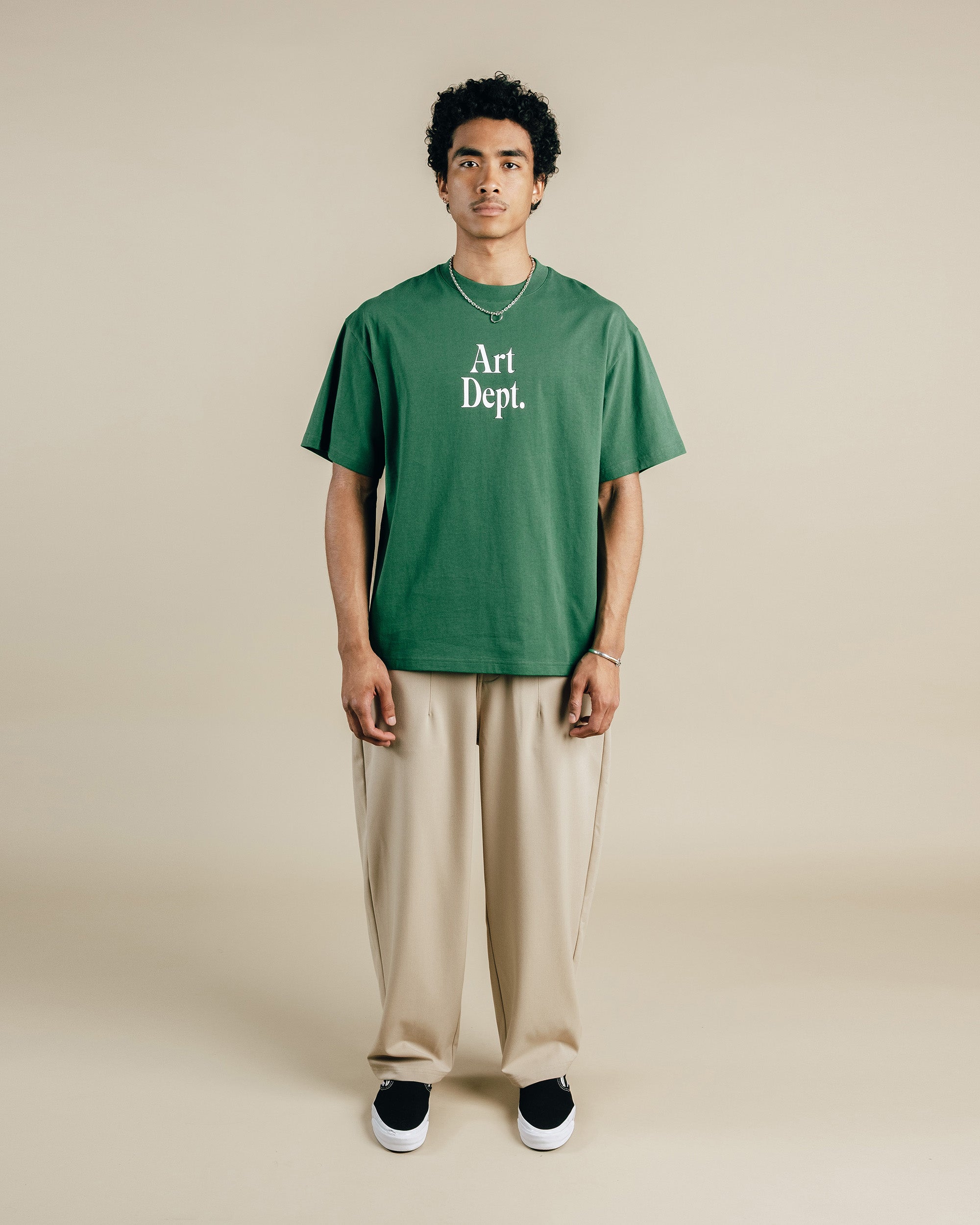 Person wearing a green 'Art Dept.' t-shirt on a beige background