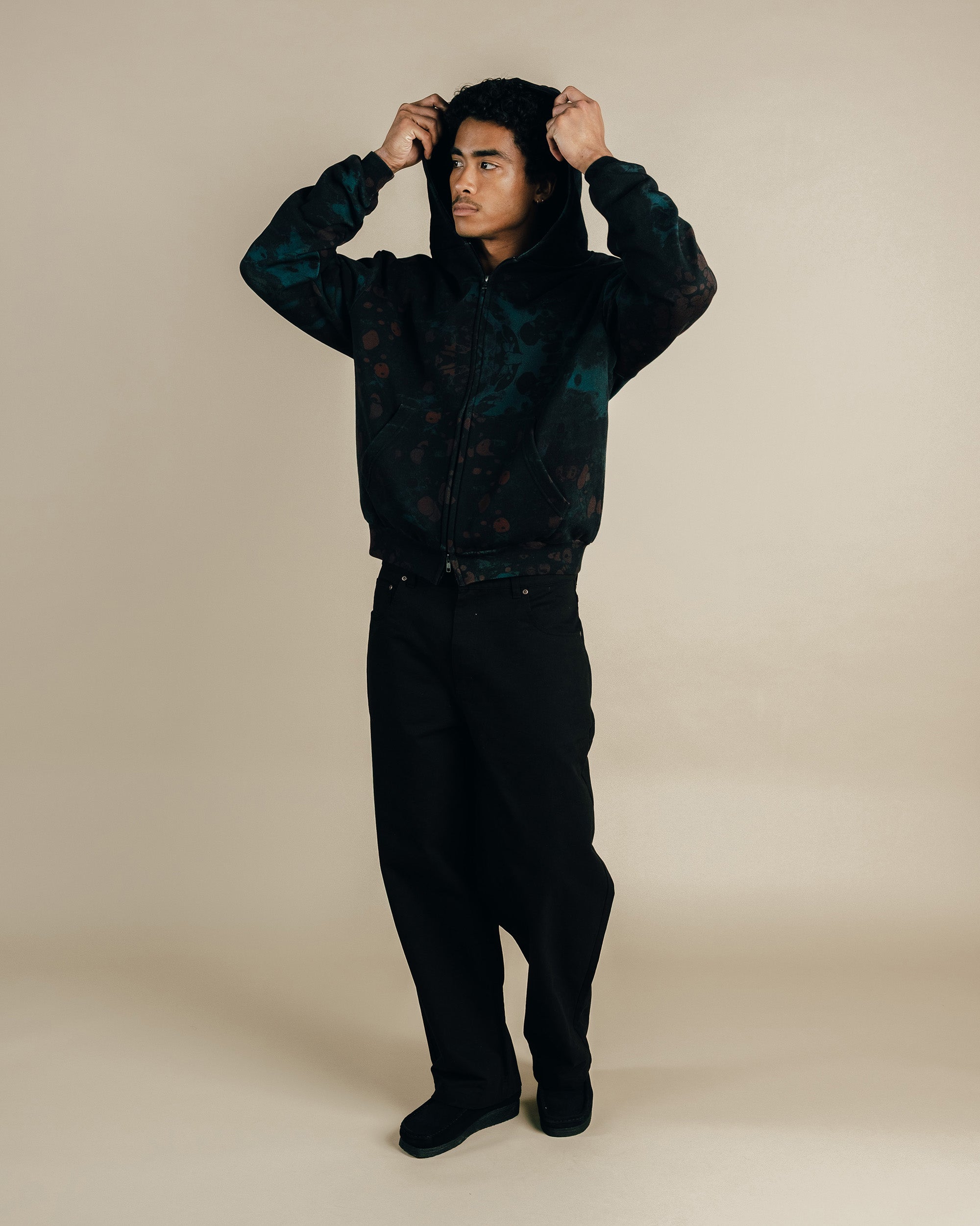 Person wearing a dark jacket and pants against a beige background