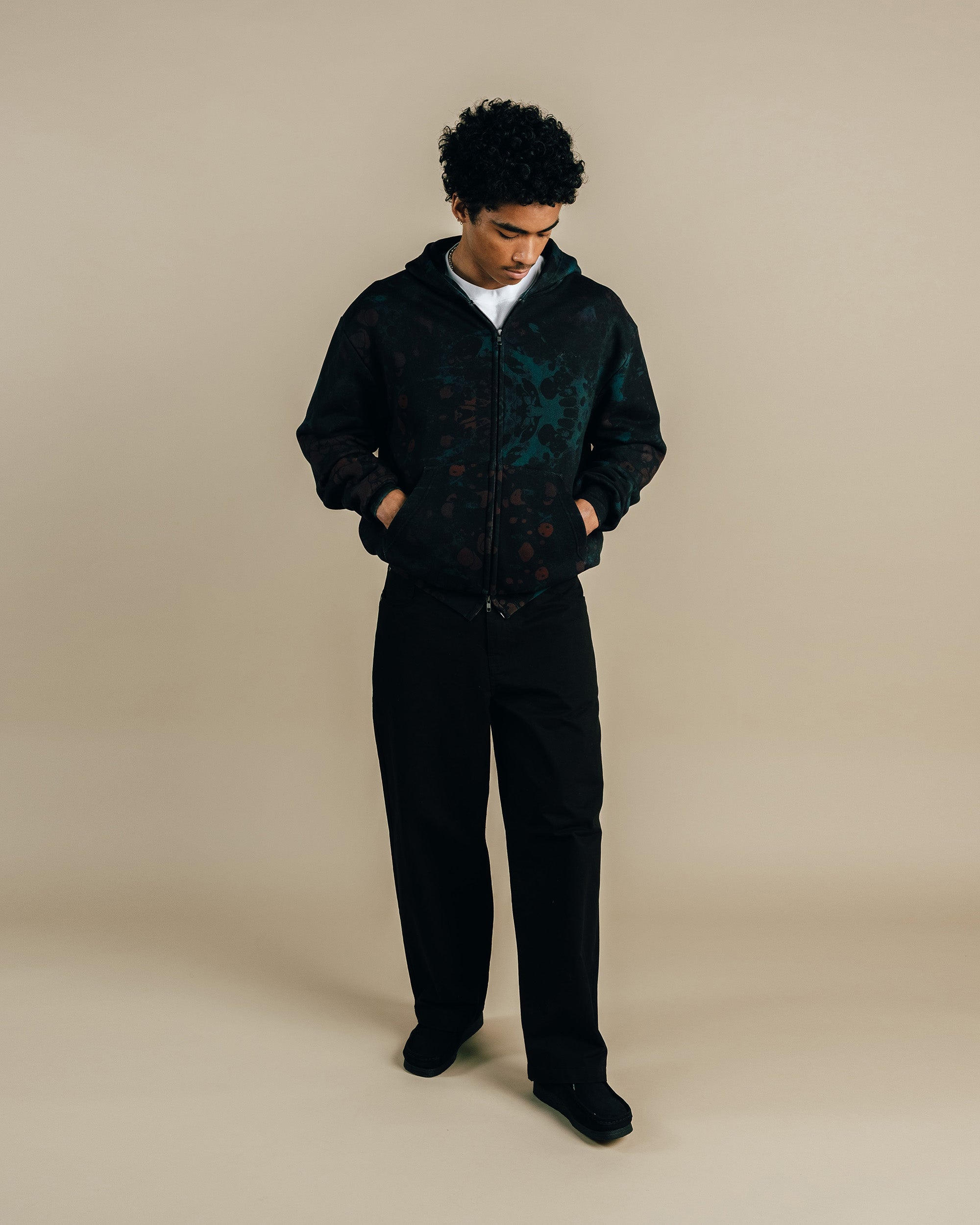 Person wearing a dark jacket and pants on a beige background