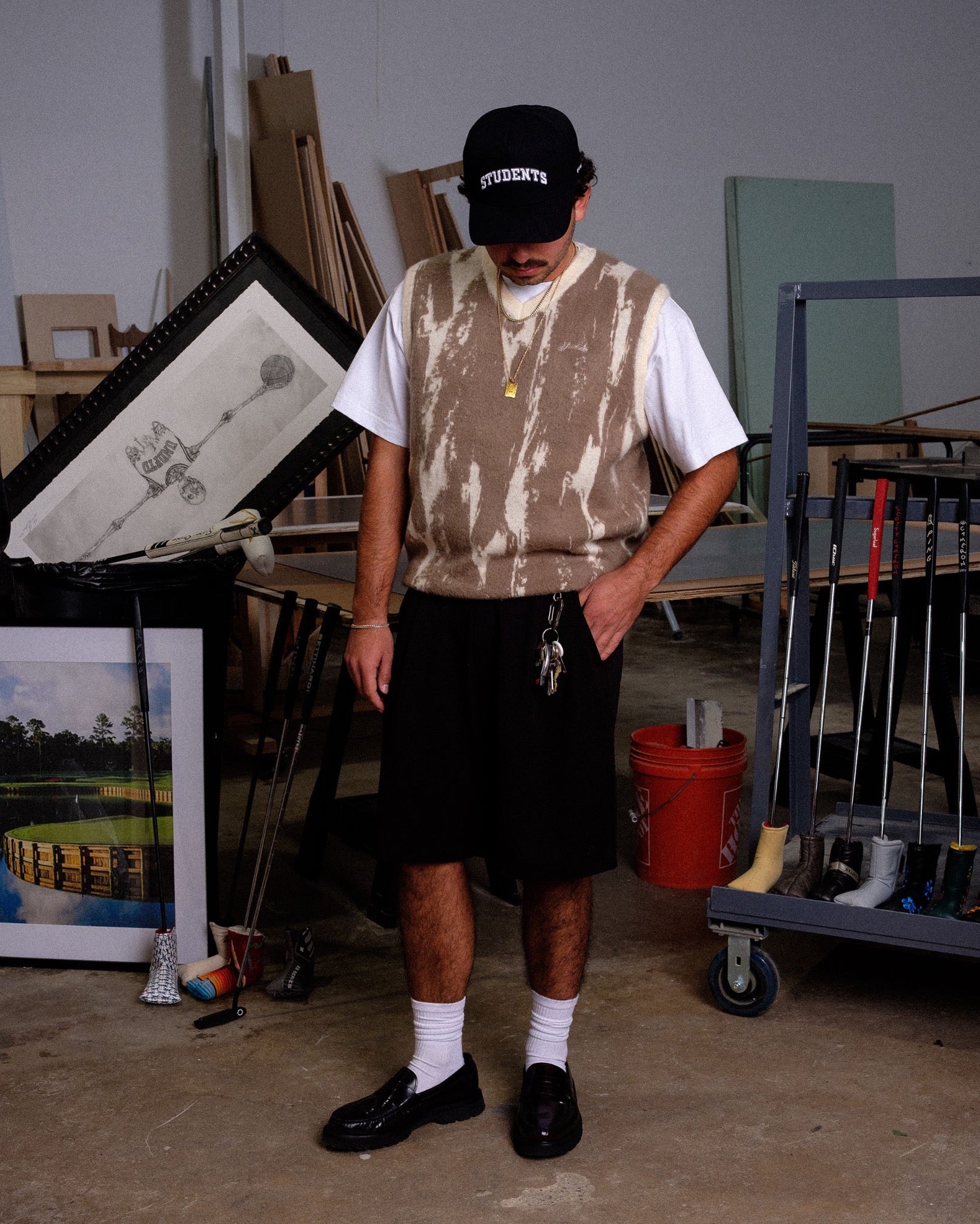 Person wearing a sleeveless shirt and shorts in an art studio setting