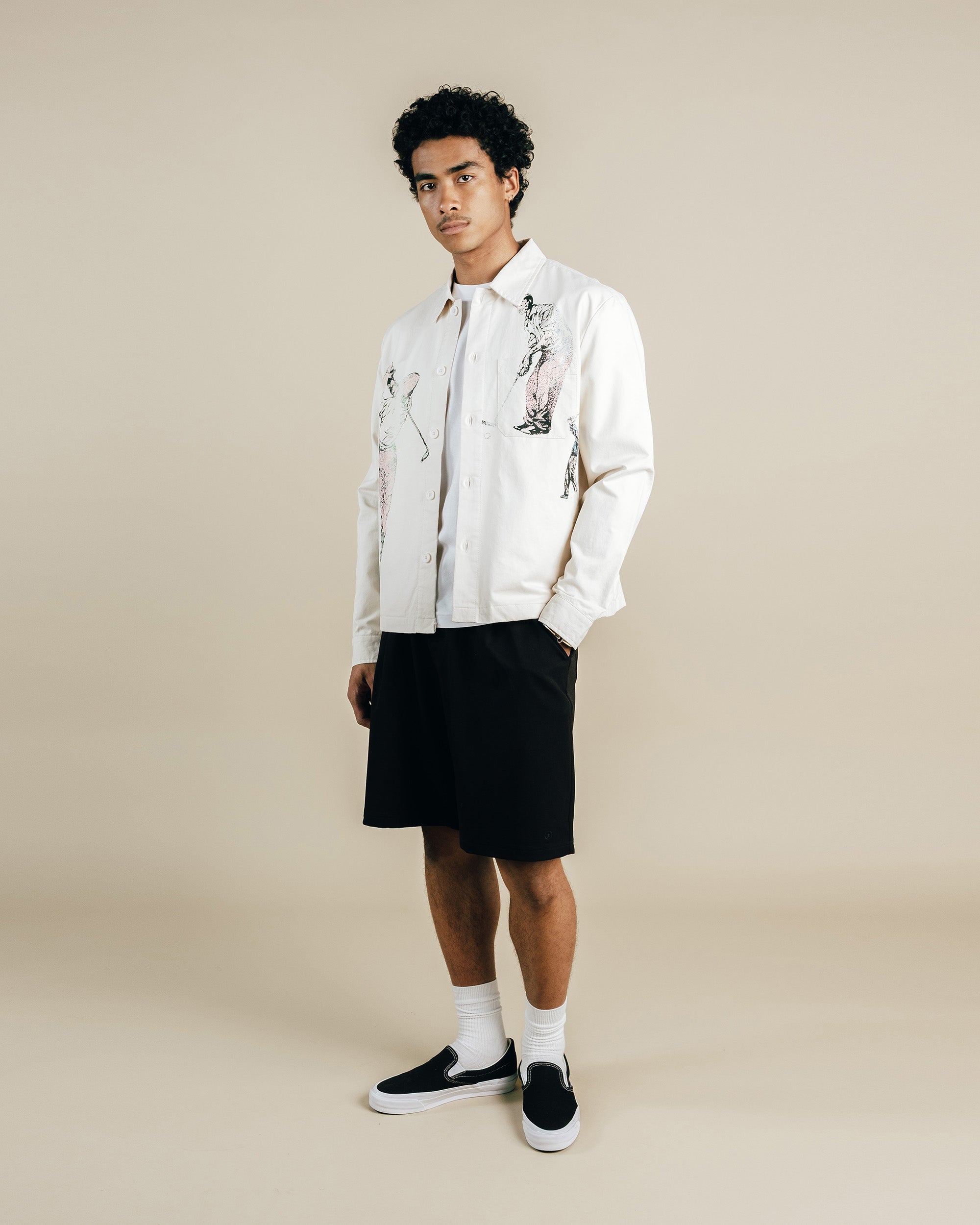 Person wearing a white shirt with black shorts on a beige background