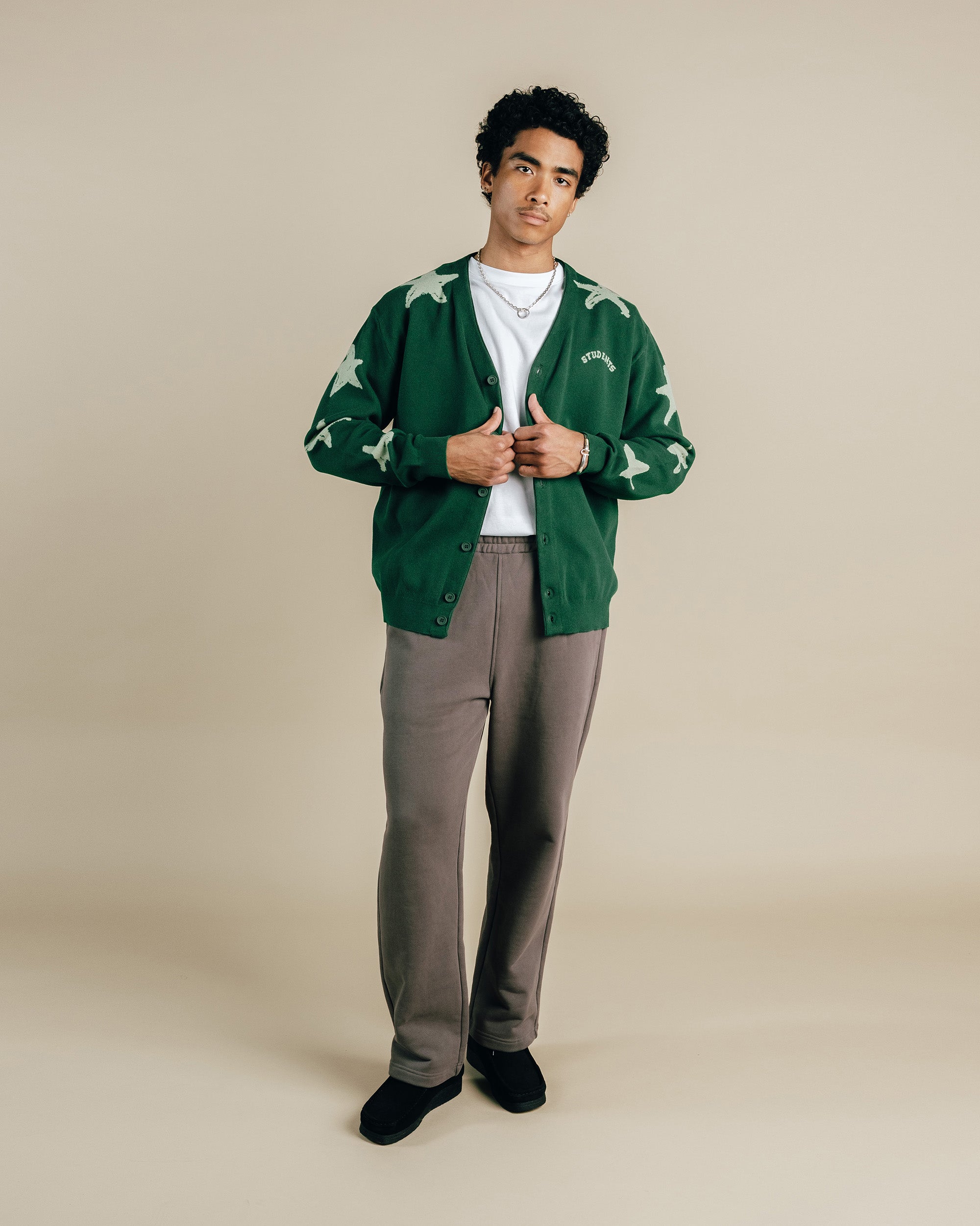 Person wearing a green cardigan with white patterns on a beige background