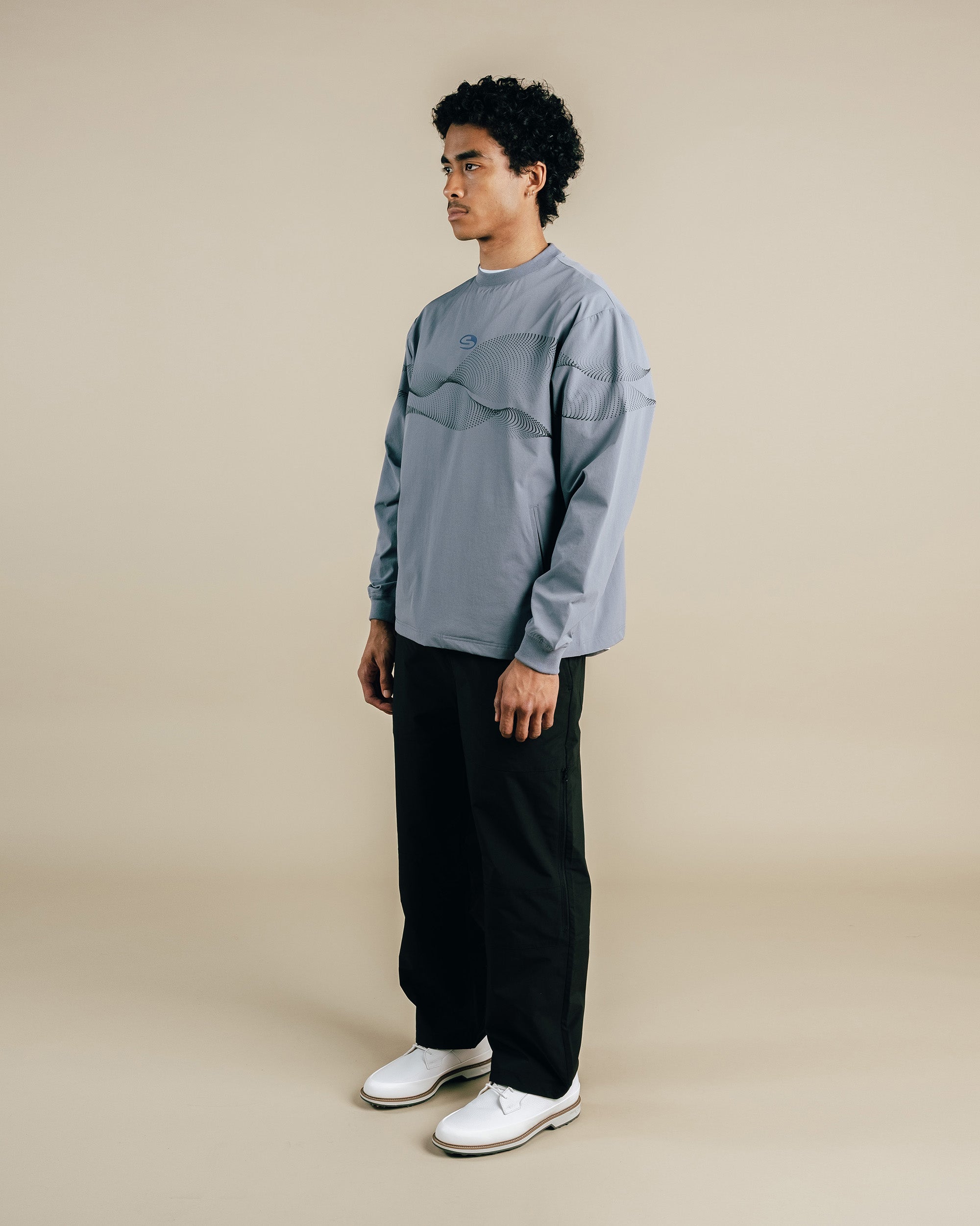 Person wearing a grey shirt and black pants on a beige background