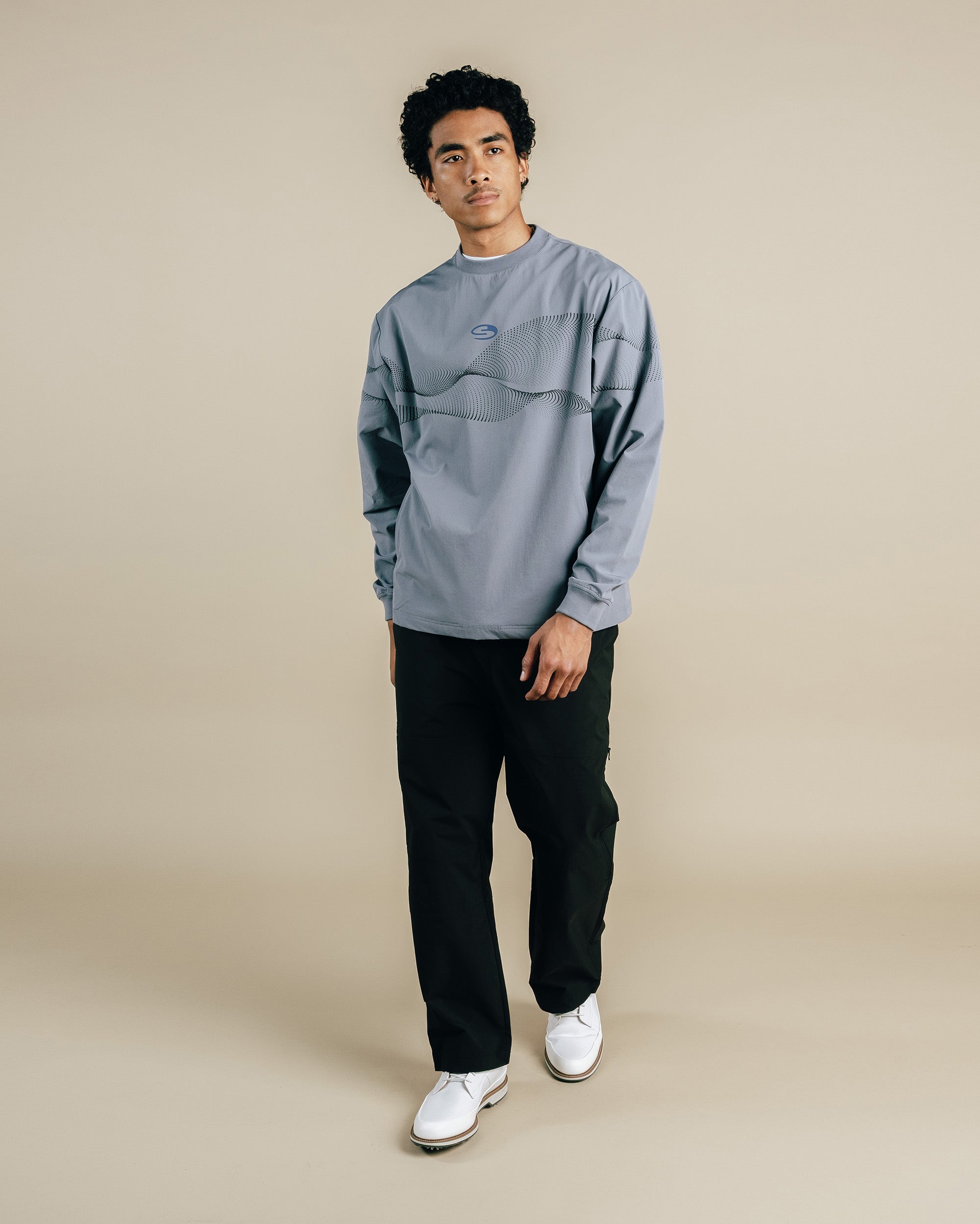 Person wearing a gray sweatshirt and black pants on a beige background