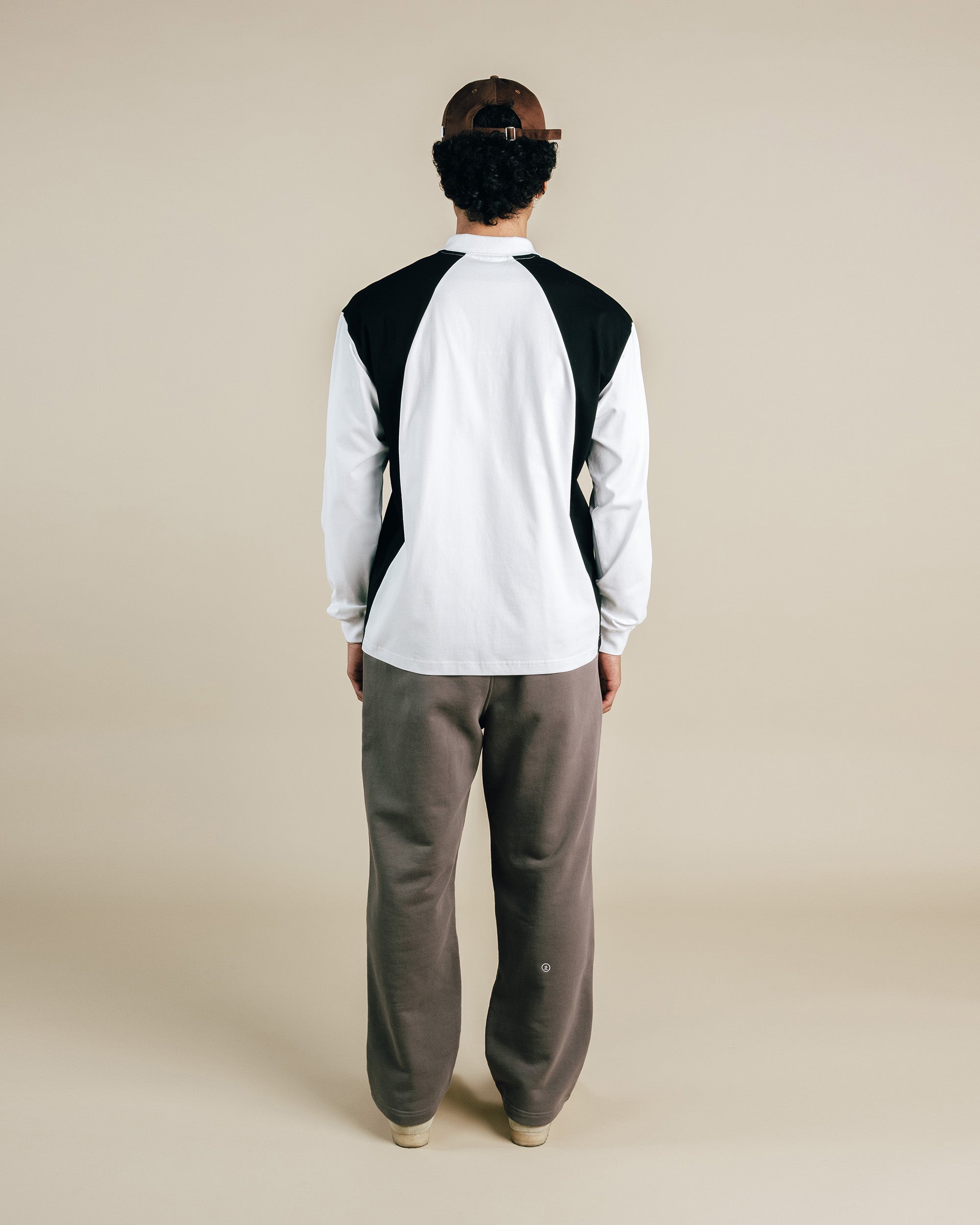 Person wearing a black and white long-sleeve shirt with gray pants on a beige background