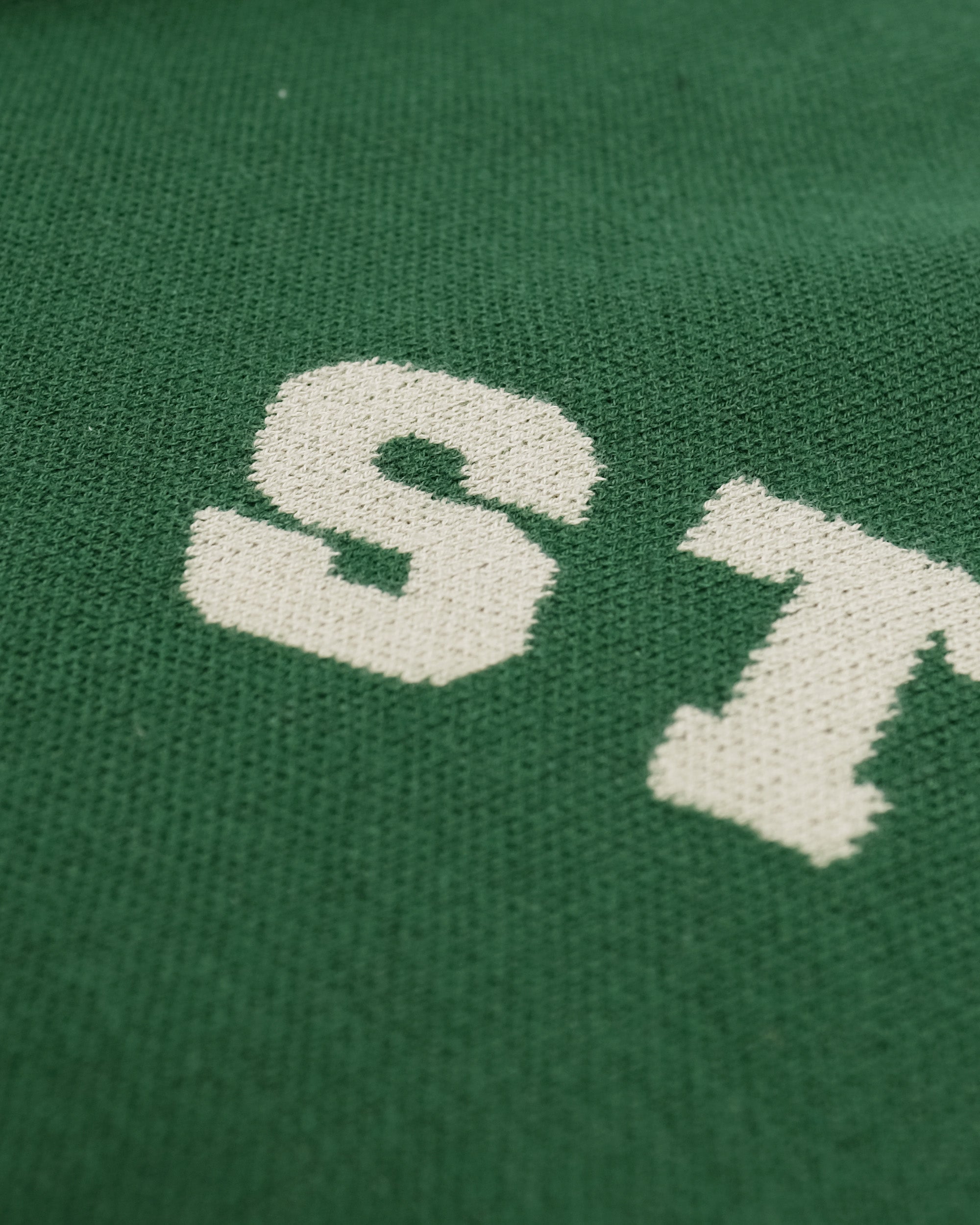 Close-up of a green fabric with a white logo on a green background
