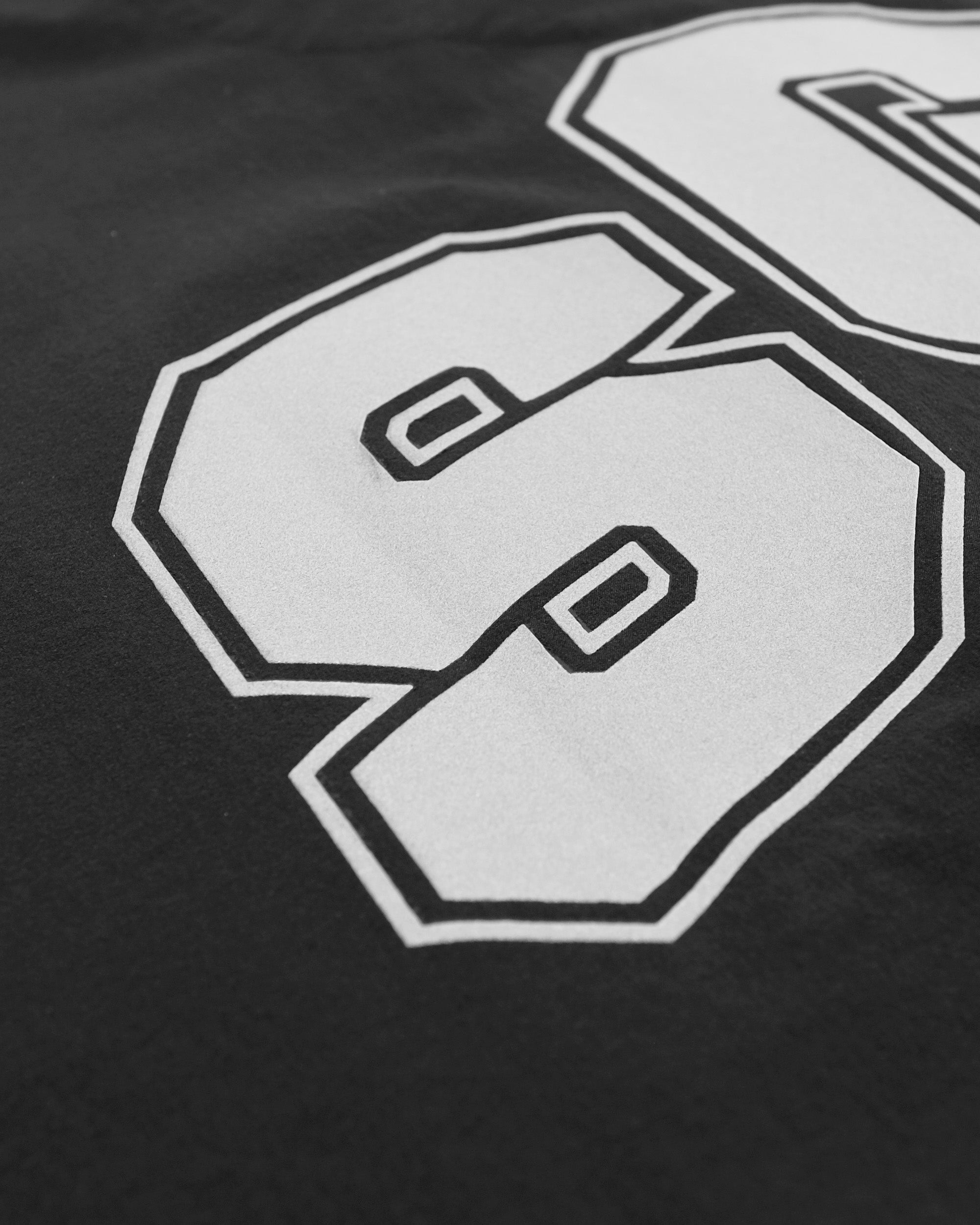 Close-up of a black t-shirt with white letter 'S' design.