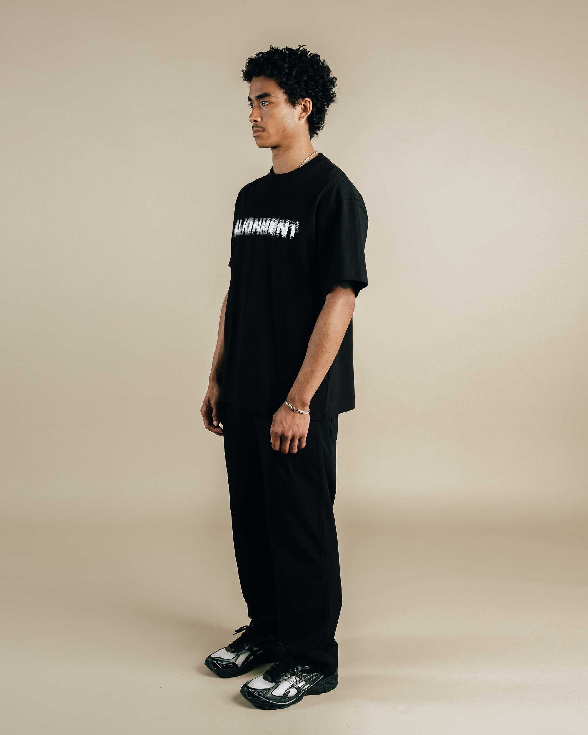 Person wearing a black t-shirt with white text on a beige background