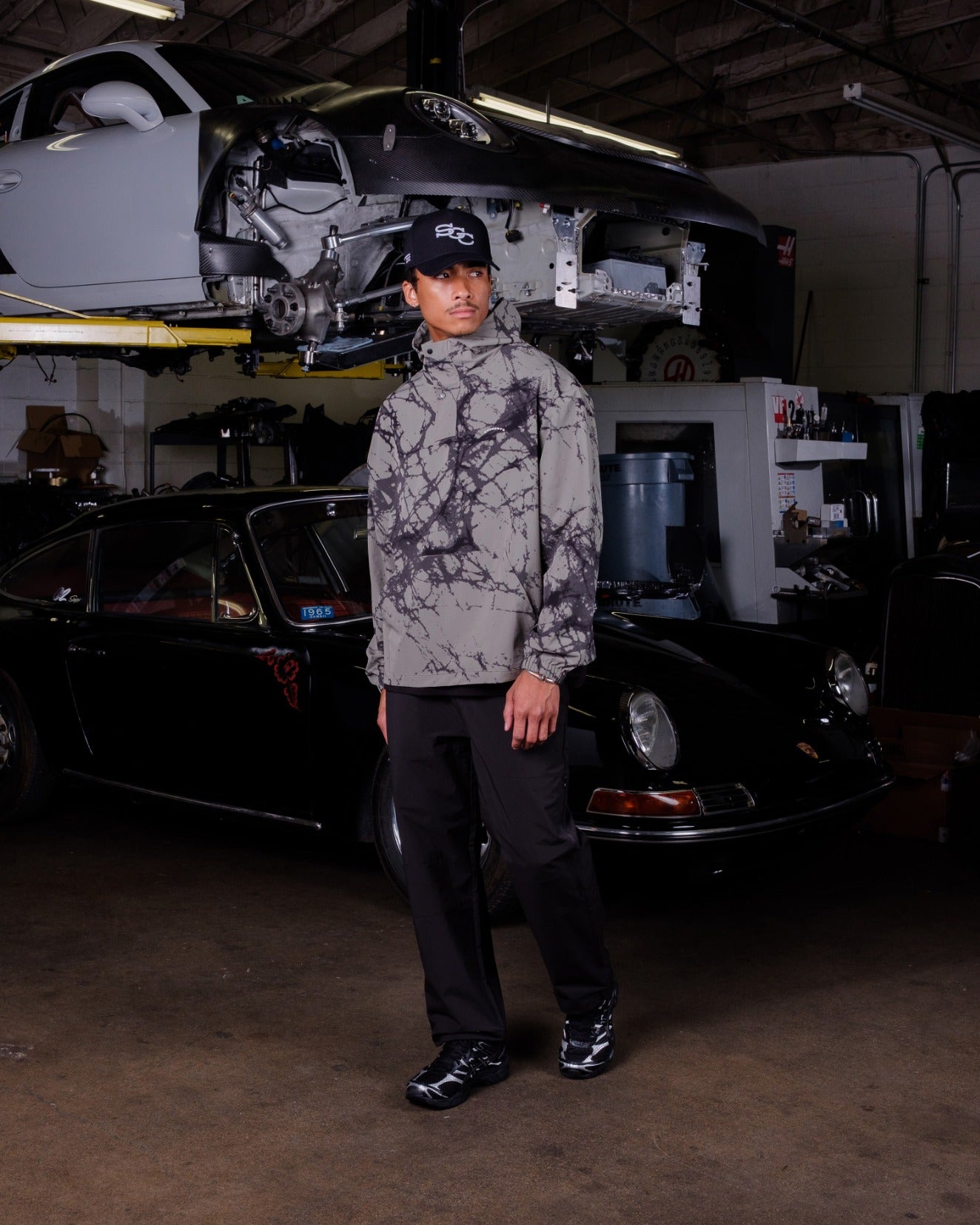 Person standing in a garage with a car and equipment in the background