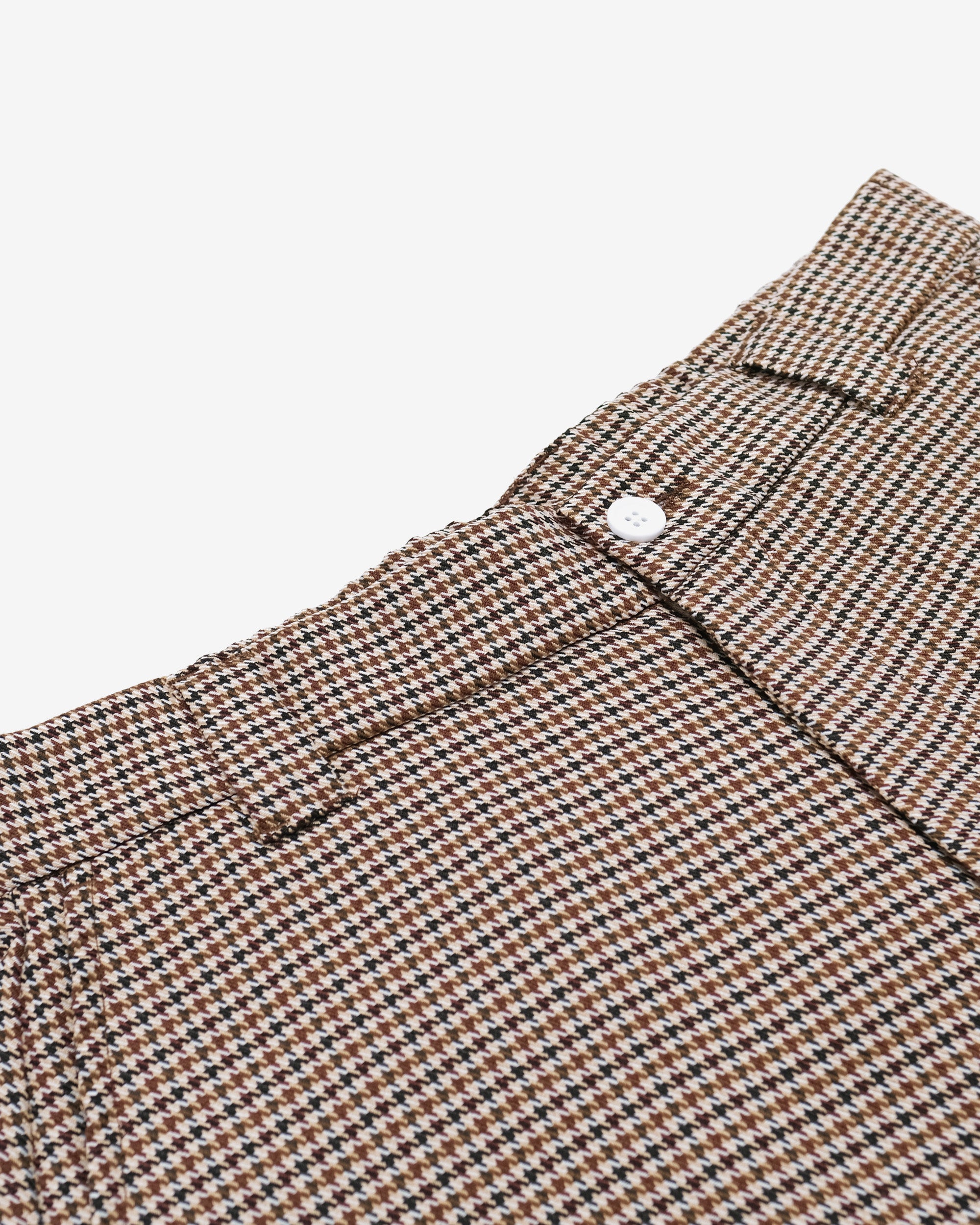 Close-up of a brown and black houndstooth patterned fabric with a button on a light gray background.