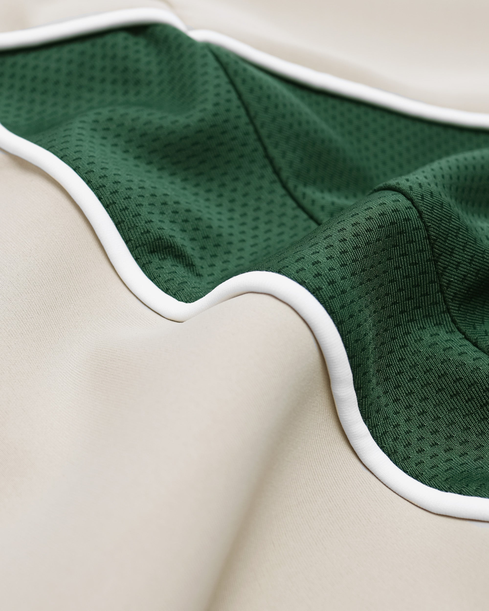 Green textured fabric with white trim on a beige background