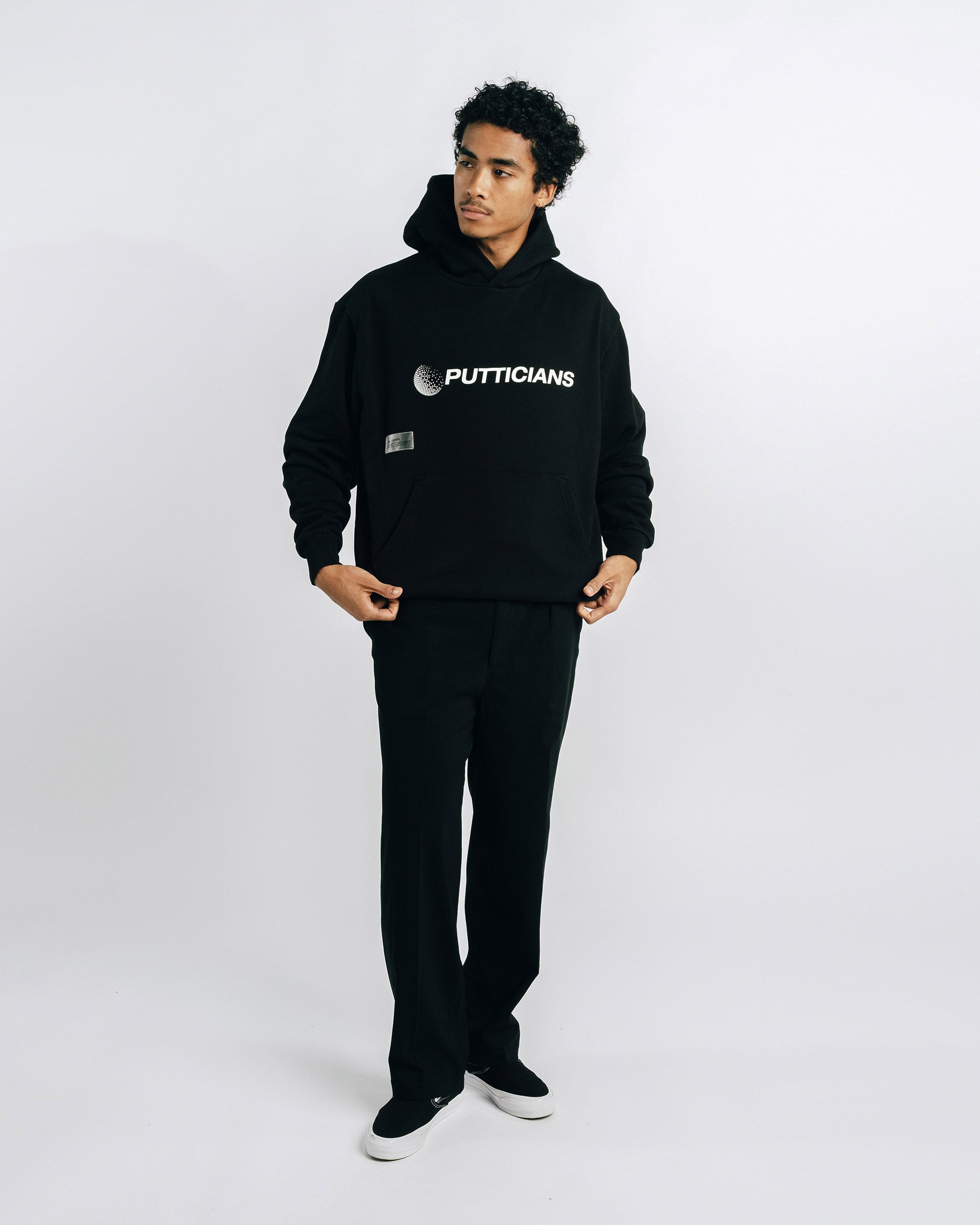 Person wearing a black hoodie with 'PUTTICIANS' logo on a white background