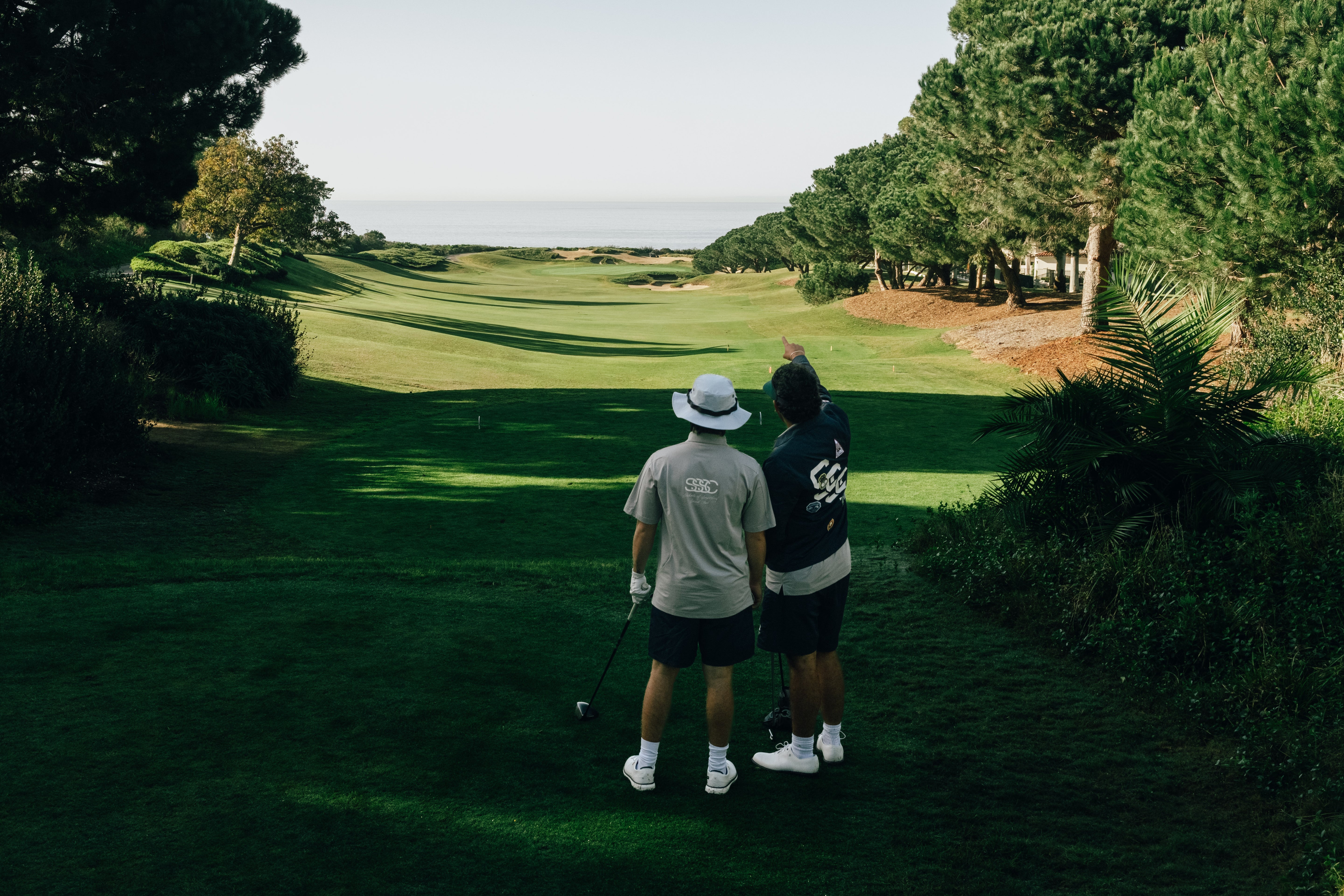 Two golfers on a golf course with trees and greenery around