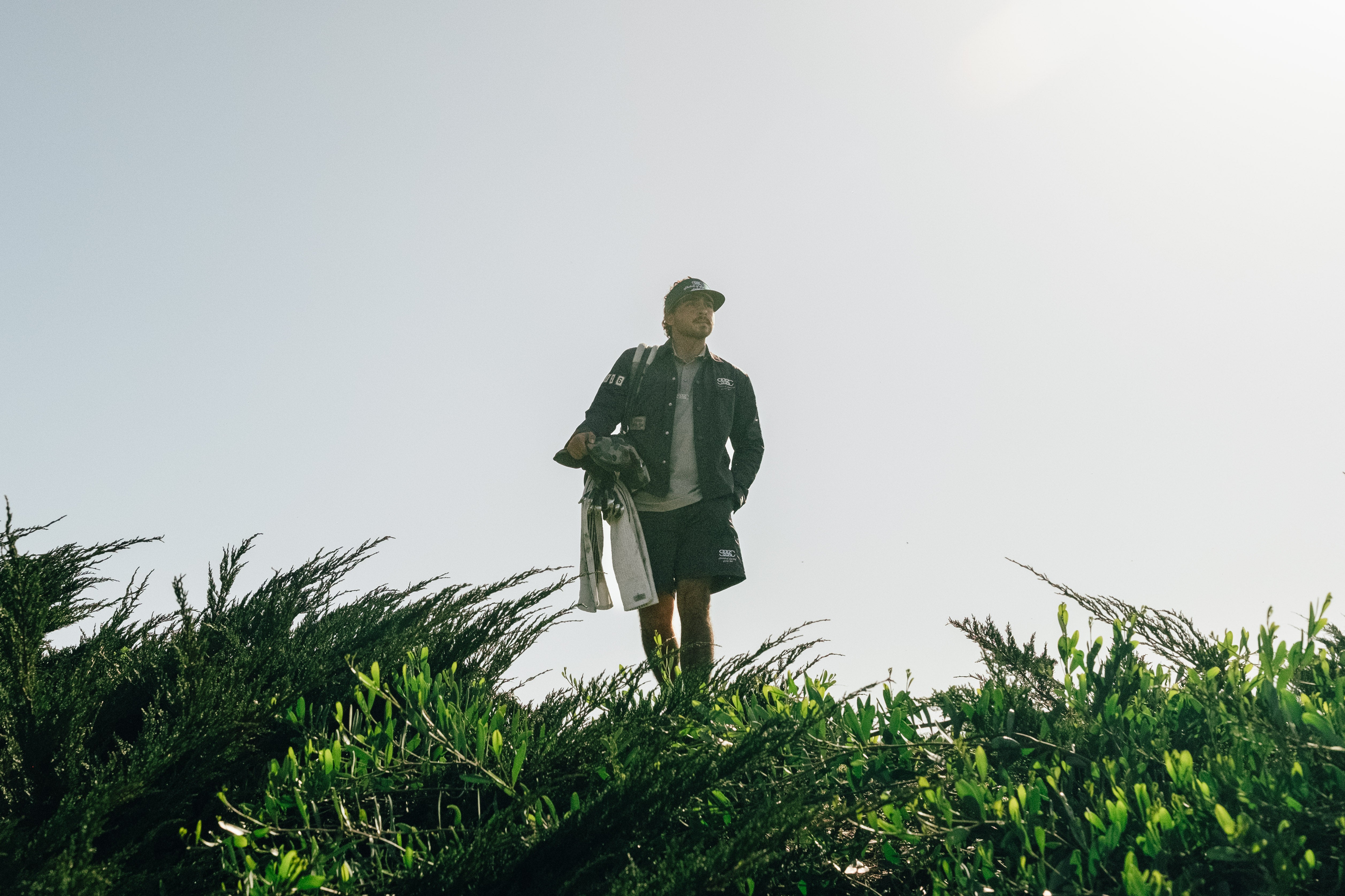 Person standing on a grassy hill with a clear sky